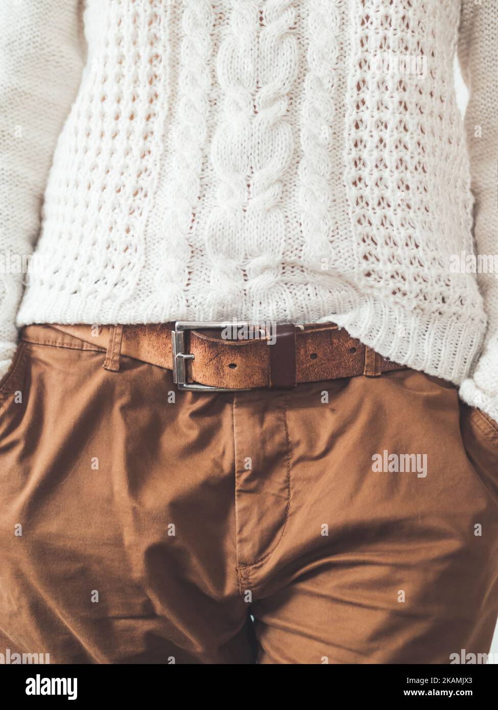 Donna in maglia bianca con pattinatore scandinavo e pantaloni chino marroni con cintura in pelle. Abbigliamento casual per il tempo. urb moderna Foto Stock