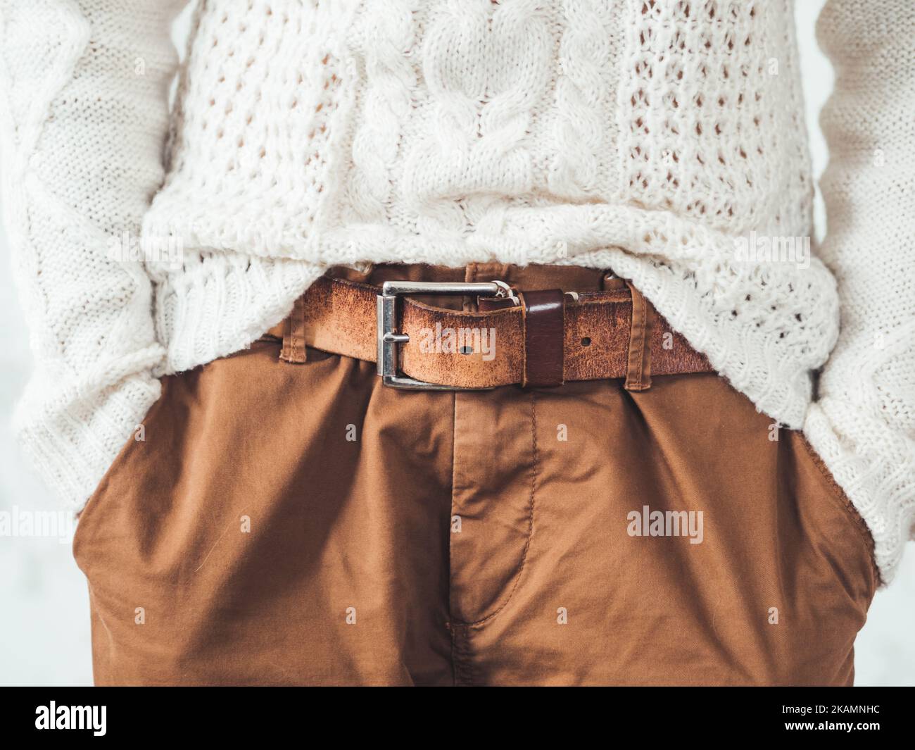 Donna in maglia bianca con motivo scandinavo e pantaloni chino marroni con cintura in pelle. Abbigliamento casual per il tempo. Moderno ur Foto Stock