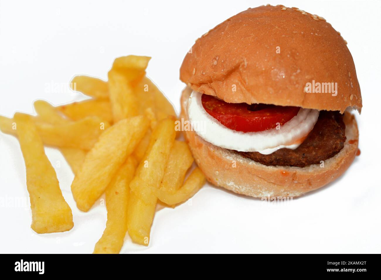 focus selettivo del panino hamburger di manzo con fette di anelli di cipolla e pomodori, con patatine fritte dita di patate isolate sul dorso bianco Foto Stock