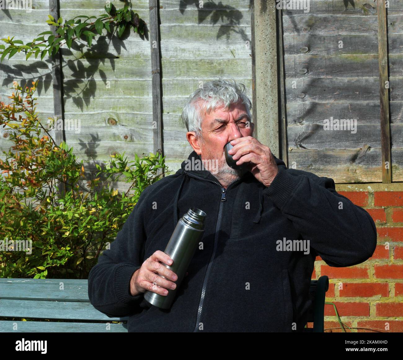 Uomo che beve caffè o tè da un pallone da vuoto thermos a basse temperature. Foto Stock