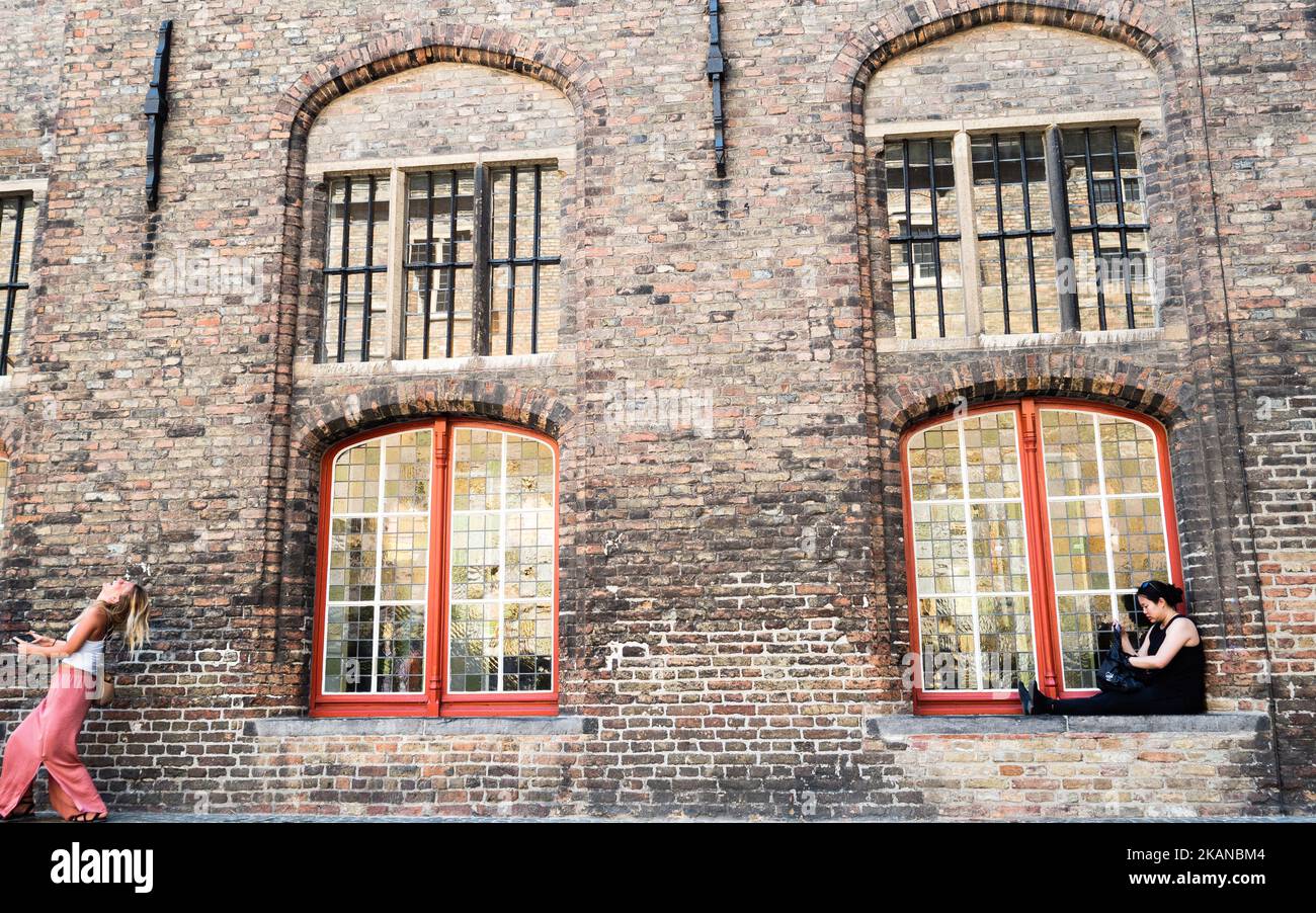 Una donna seduta su una finestra a Bruges, Belgio, il 27 maggio 2017. Durante uno dei giorni più caldi dell'anno, Bruges è stata la destinazione scelta da migliaia di turisti provenienti da tutto il mondo. Questa è la capitale e la città più grande della provincia delle Fiandre Occidentali nella regione fiamminga del Belgio, nel nord-ovest del paese. Essendo Bruges un'enorme destinazione turistica, i turisti hanno molte scelte per godersi la città, come escursioni in carrozza trainata da cavalli, tour dei canali in barca o semplicemente passeggiate nel centro storico della città. (Foto di Romy Arroyo Fernandez/NurPhoto) *** Please use Credit from Foto Stock
