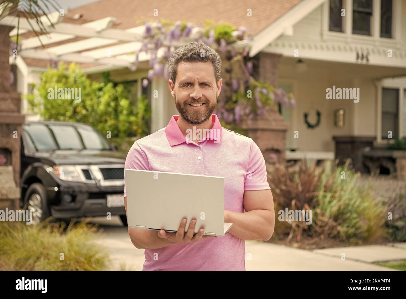 felice uomo bearded realtor acquistare casa online su laptop, presentazione Foto Stock