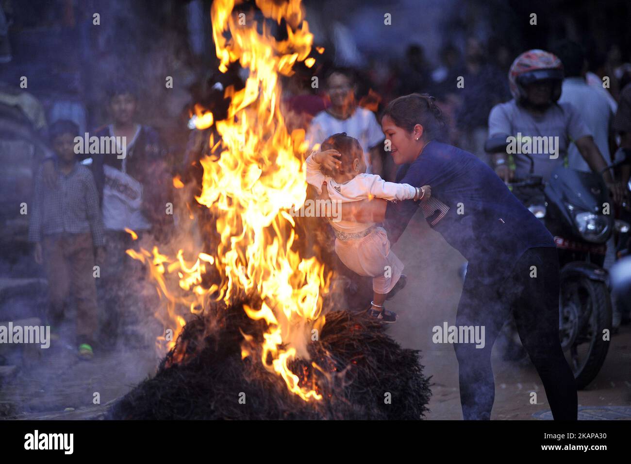 I devoti nepalesi oscillano il loro bambino sopra l'effigia bruciante della paglia del demone Ghantakarna durante il festival di Gathemangal celebrato a Bhaktapur, Nepal venerdì 21 luglio 2017. Gathemangal è un festival che celebra la sconfitta del mitico demone Ghantak (Photo by Narayan Maharjan/NurPhoto) *** Please use Credit from Credit Field *** Foto Stock