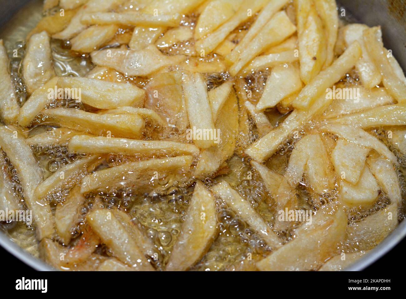 Primo piano di patate fritte francesi frittura in olio bollente in una friggitrice a casa. Patatine fritte, cibo spazzatura, patatine fritte fatte in casa, sele Foto Stock