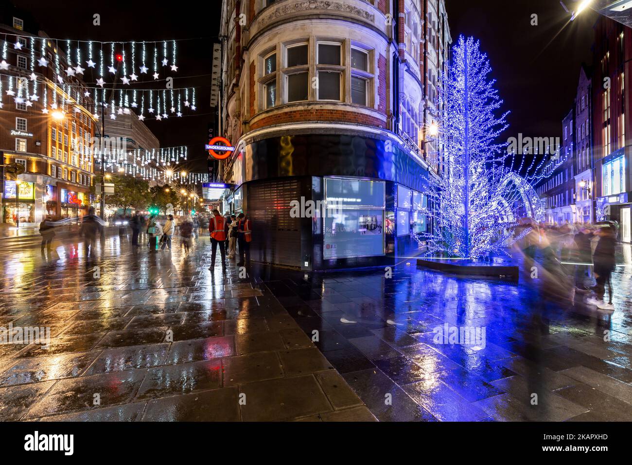 Illuminazioni natalizie all'angolo di oxford e South Muse Streets.Blue christmas mostre riflesse nei marciapiedi bagnati.Xmas 2022 Foto Stock