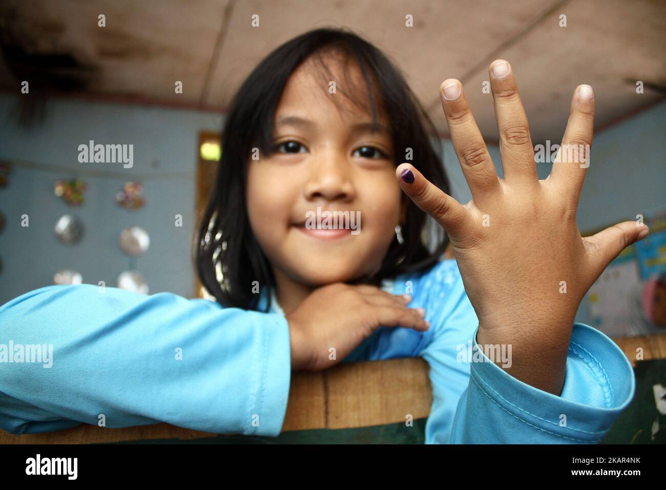 Una ragazza mostra il suo dito blu, un segno che ha ottenuto il vaccino del morbillo e della rosolia in un servizio sanitario integrato posti nel villaggio di Wanasari, Java occidentale, il 8 settembre 2017. Il governo indonesiano si rivolge a un minimo del 95% o a 34.964.384 bambini in tutta l'Indonesia di età compresa tra 9 mesi e 15 anni, ottenendo il vaccino contro la RM, attraverso il programma della campagna di immunizzazione, che inizia da agosto a settembre 2017 e agosto-settembre 2018. La campagna di immunizzazione contro la RM è la realizzazione di un programma governativo per eliminare il morbillo e la rosolia in Indonesia entro il 2020. (Foto di Aditya Irawan/NurPhot Foto Stock