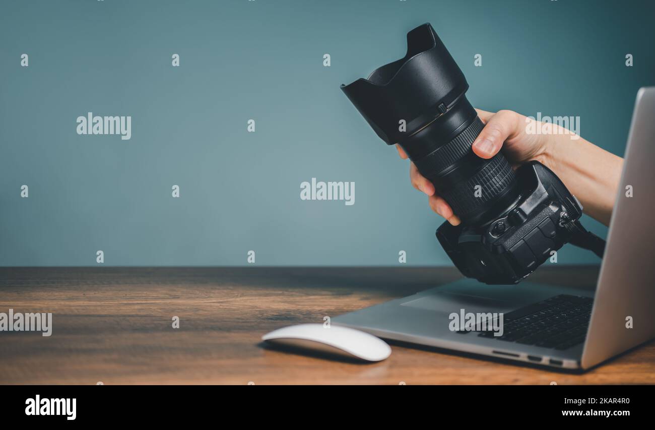 Acquista Camera Online Concept, tenendo la fotocamera mano e sporgendo dal monitor del computer portatile schermo. Foto Stock
