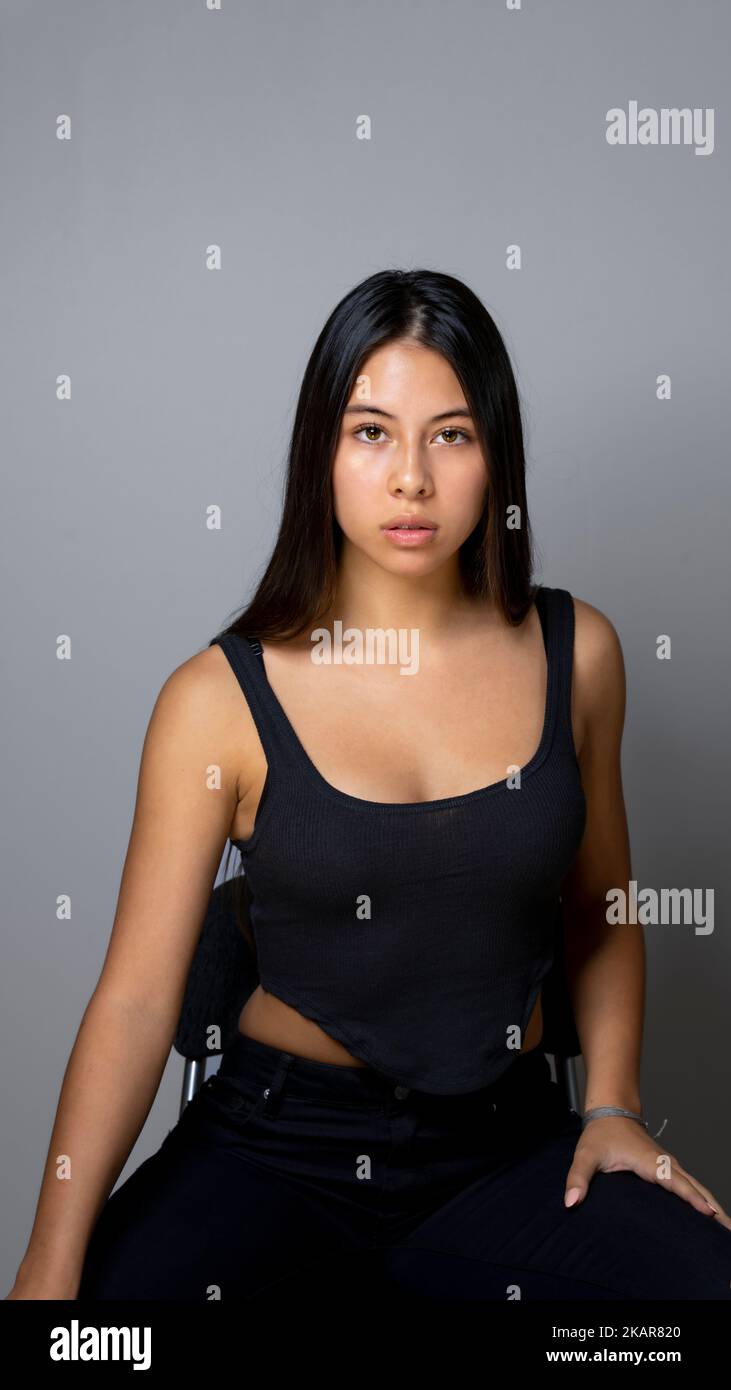 Donna multirazziale dall'aspetto serio seduta con Copy Space sopra su uno sfondo grigio Foto Stock