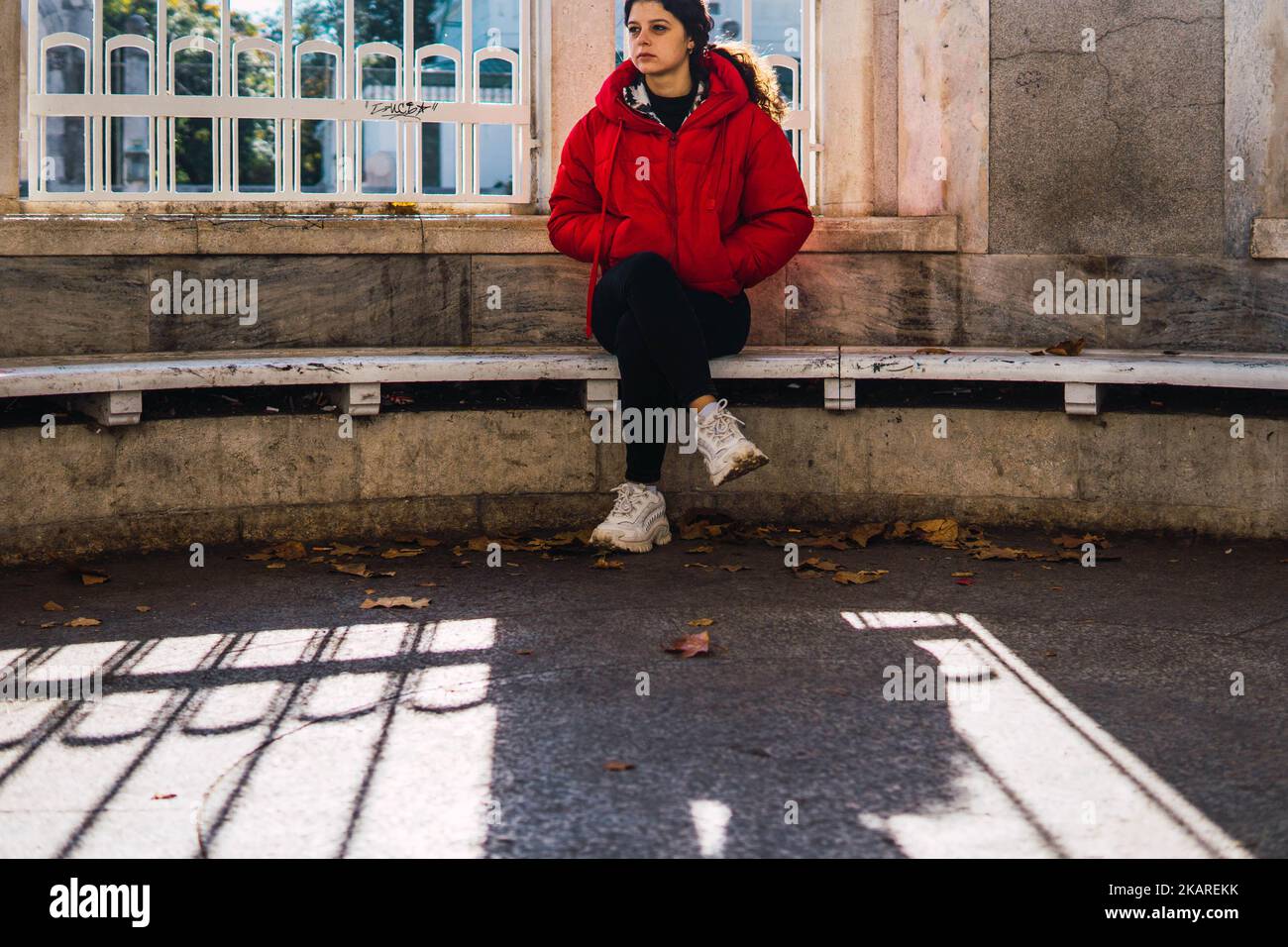 donna seduta a gambe incrociate su una panca di pietra Foto Stock