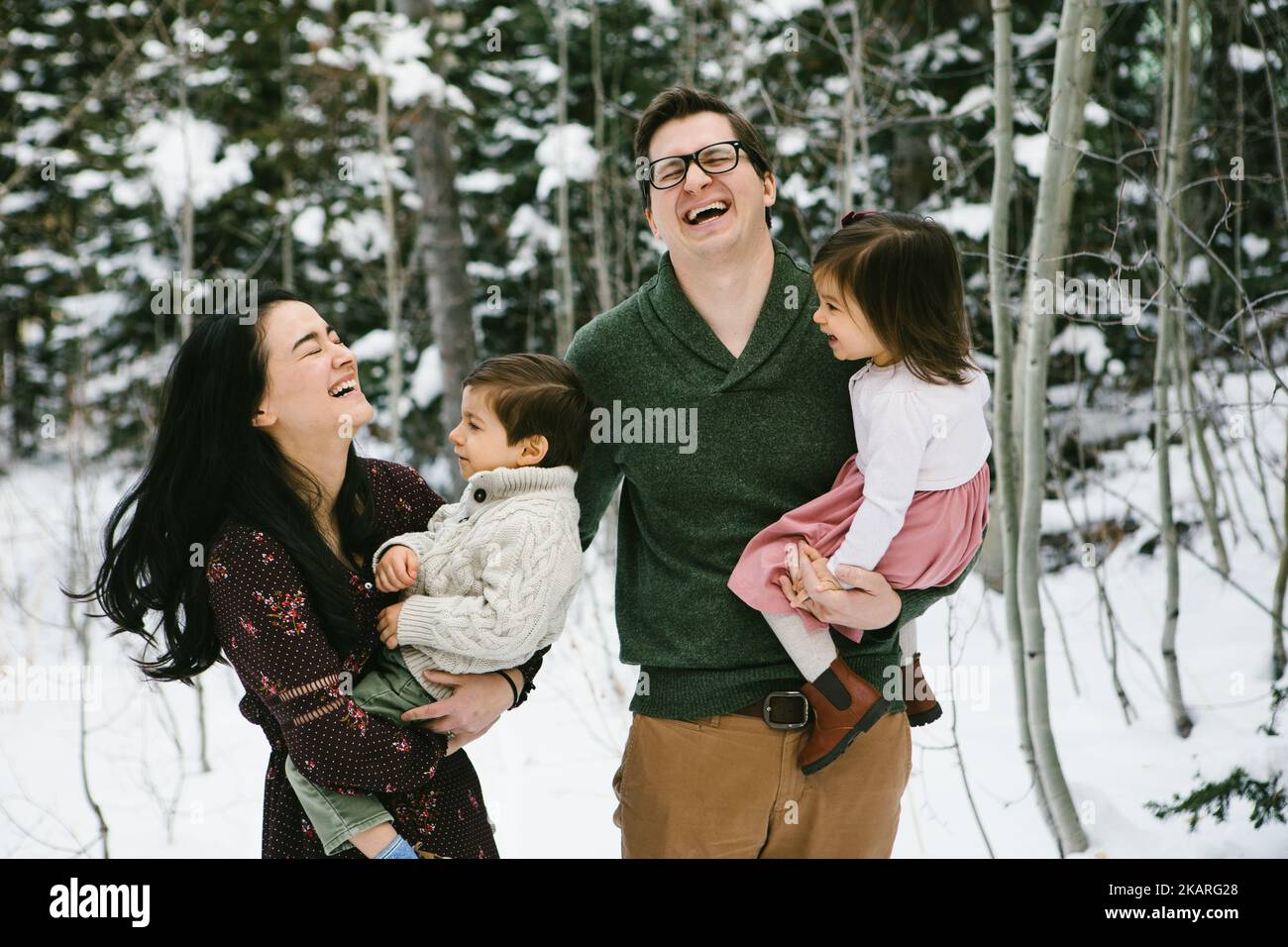 La famiglia ride con due piccoli bambini nella foresta di neve Foto Stock