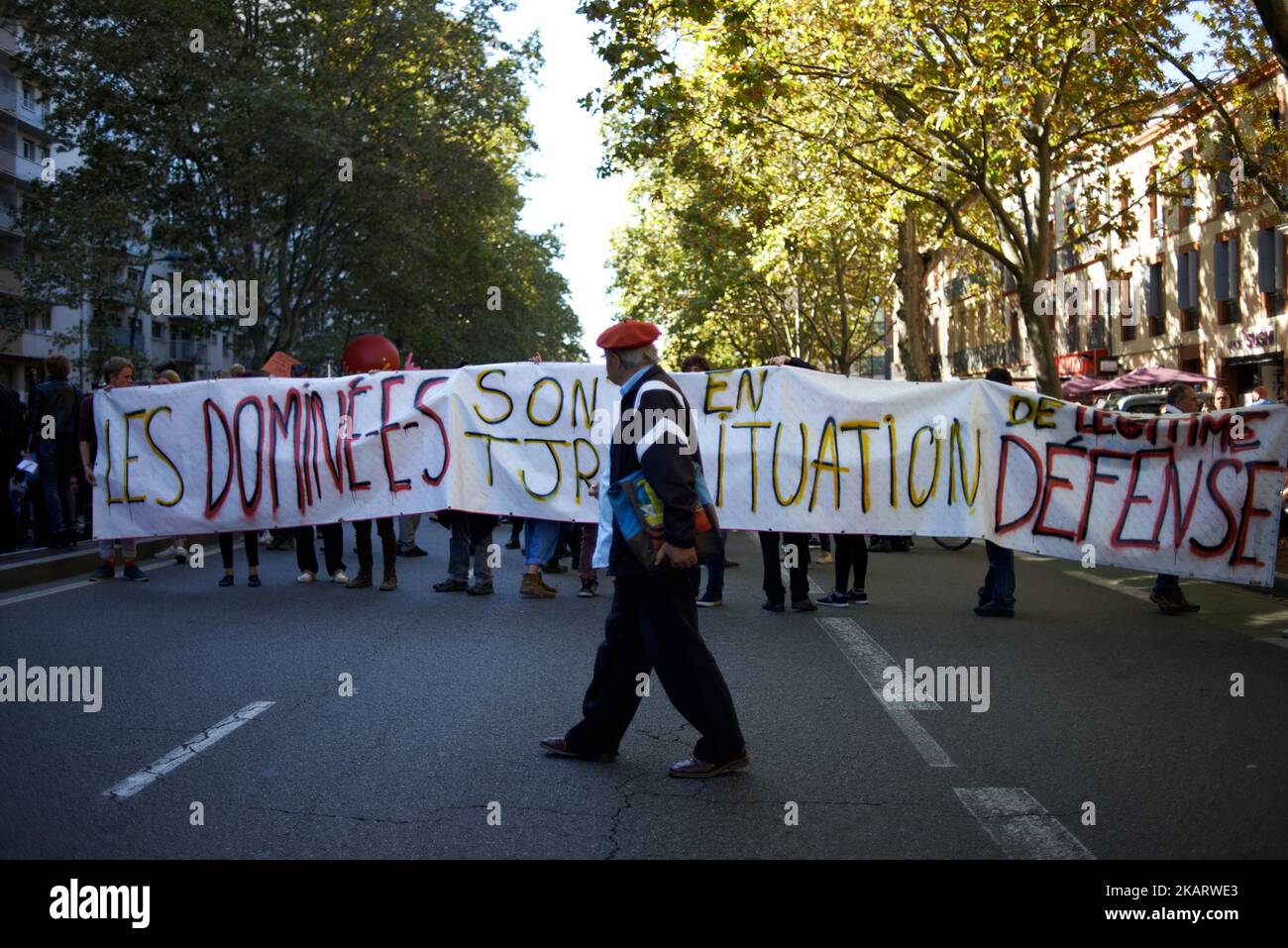 Un protester cammina davanti ad una bandiera che legge "le persone subjugated sono sempre nella situazione legittima di difesa”. Più di 15000 manifestanti sono scesi per le strade di Tolosa contro le riforme del nuovo Macron sul Codice di lavoro. È un giorno di azione nazionale dei funzionari pubblici contro il taglio previsto di 120 000 posti di lavoro e il congelamento della loro retribuzione. La manifestazione è stata convocata da tutti i sindacati (CGT, SUD, CFDT, ecc.), dai partiti politici (Mouvement du 1er Juillet, France Insoumise) e dalle organizzazioni giovanili. Il 10th ottobre 2017 a Tolosa, Francia. (Foto di Alain Pitton/NurPhoto) Foto Stock