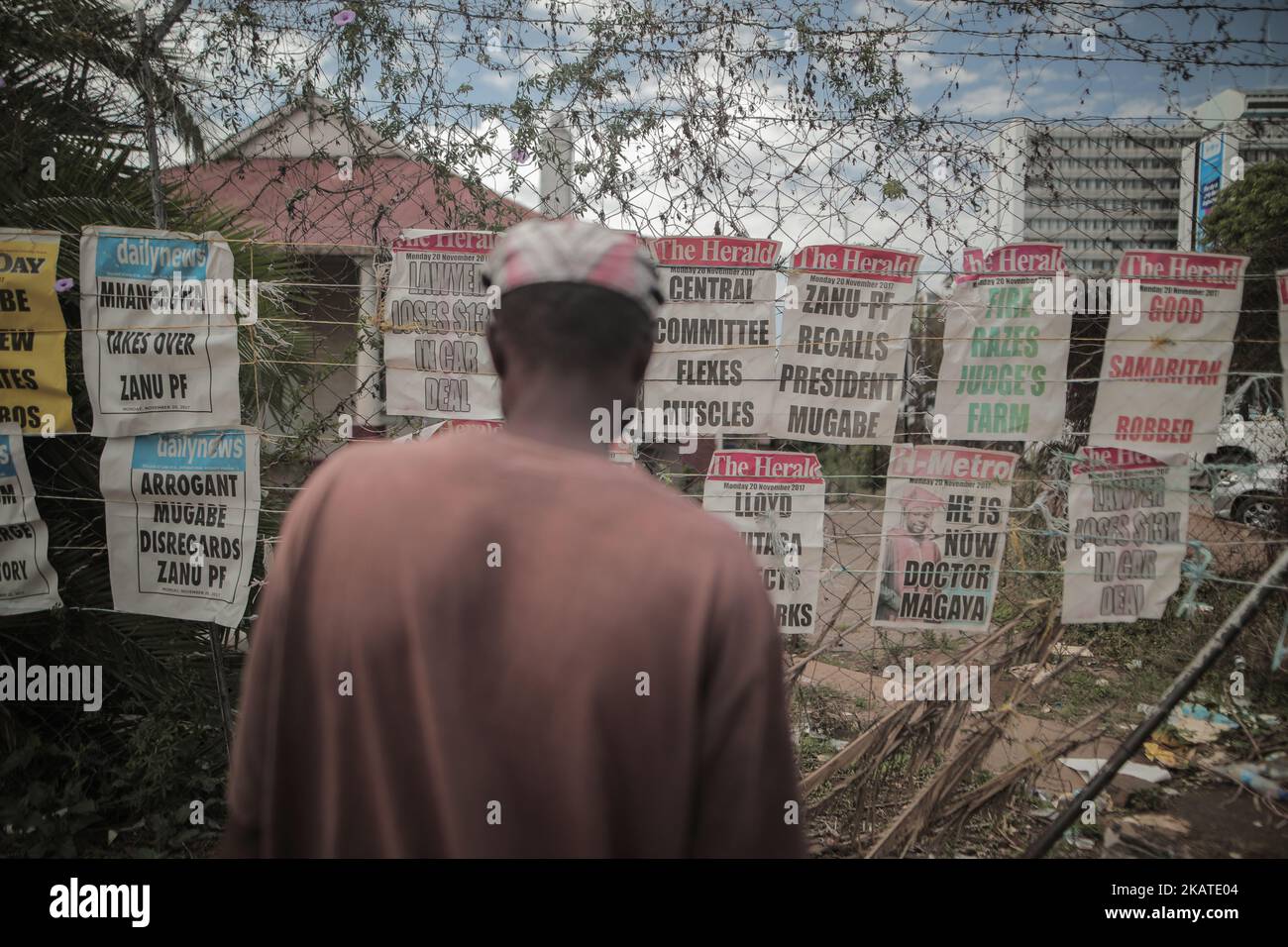Un uomo dello Zimbabwe legge i giornali appesi in una strada nella capitale Harare, Zimbawe, il 20 novembre 2017. I giornali sono tenuti giù dalle rocce per impedirli di sparare via ad un'edicola ad Harare, Zimbabwe Lunedi, 20 novembre 2017. Il presidente di lunga data Robert Mugabe ha ignorato una scadenza fissata dal partito al governo per dimettersi o affrontare i procedimenti di impeachment, mentre gli abitanti dello Zimbabwe hanno stordito per la sua mancanza di dimissioni durante un discorso nazionale hanno promesso ulteriori proteste per fargli uscire. (Foto di Belal Khaled/NurPhoto) Foto Stock