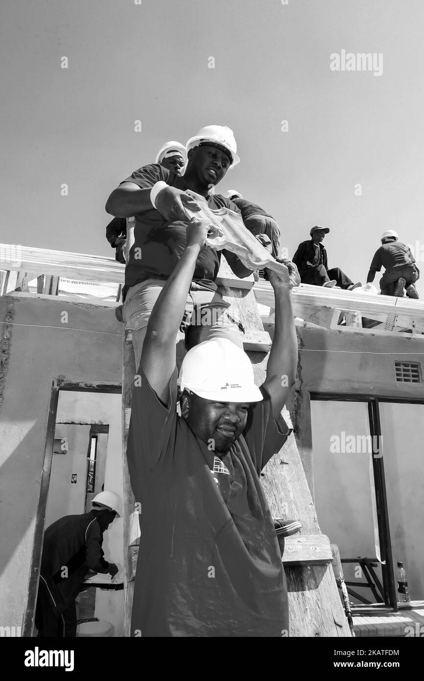 Diversi membri della comunità si uniscono allo staff di PWC nella costruzione di una casa a basso costo come squadra a Soweto Foto Stock