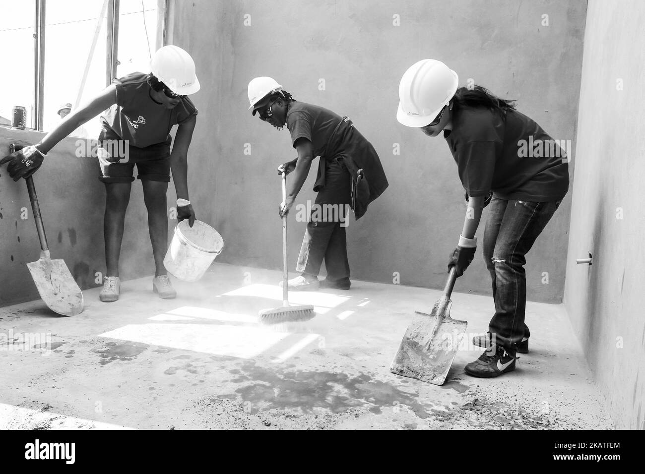 Diversi membri della comunità si uniscono allo staff di PWC nella costruzione di una casa a basso costo come squadra a Soweto Foto Stock