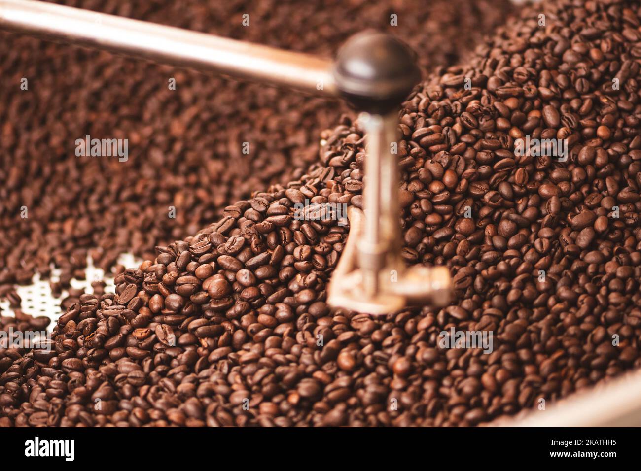 Tostatura dei chicchi di caffè in una vecchia macchina professionale per la tostatura del caffè o in primo piano Foto Stock