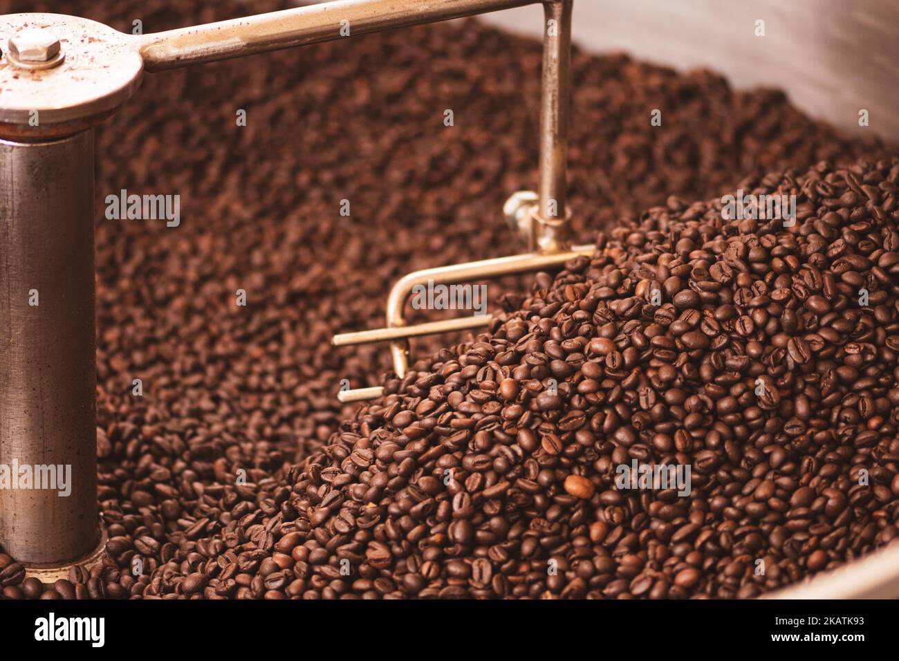 Tostatura dei chicchi di caffè in una vecchia macchina professionale per la tostatura del caffè o in primo piano Foto Stock