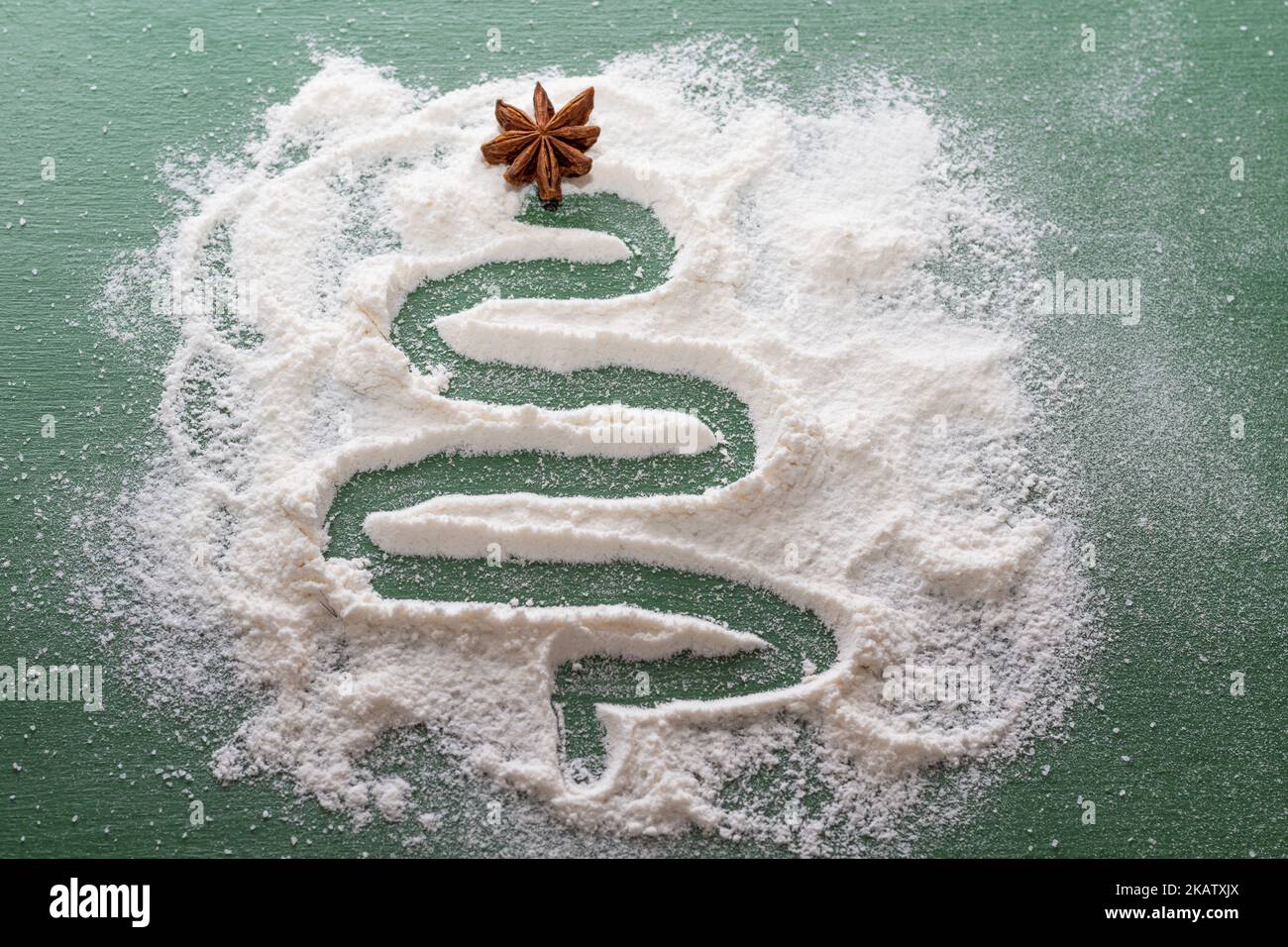Un albero di Natale dipinto di farina come da neve con una stella secca di anice su sfondo verde. Cucina di Natale: Abete fatto di quattro, ingredi Foto Stock