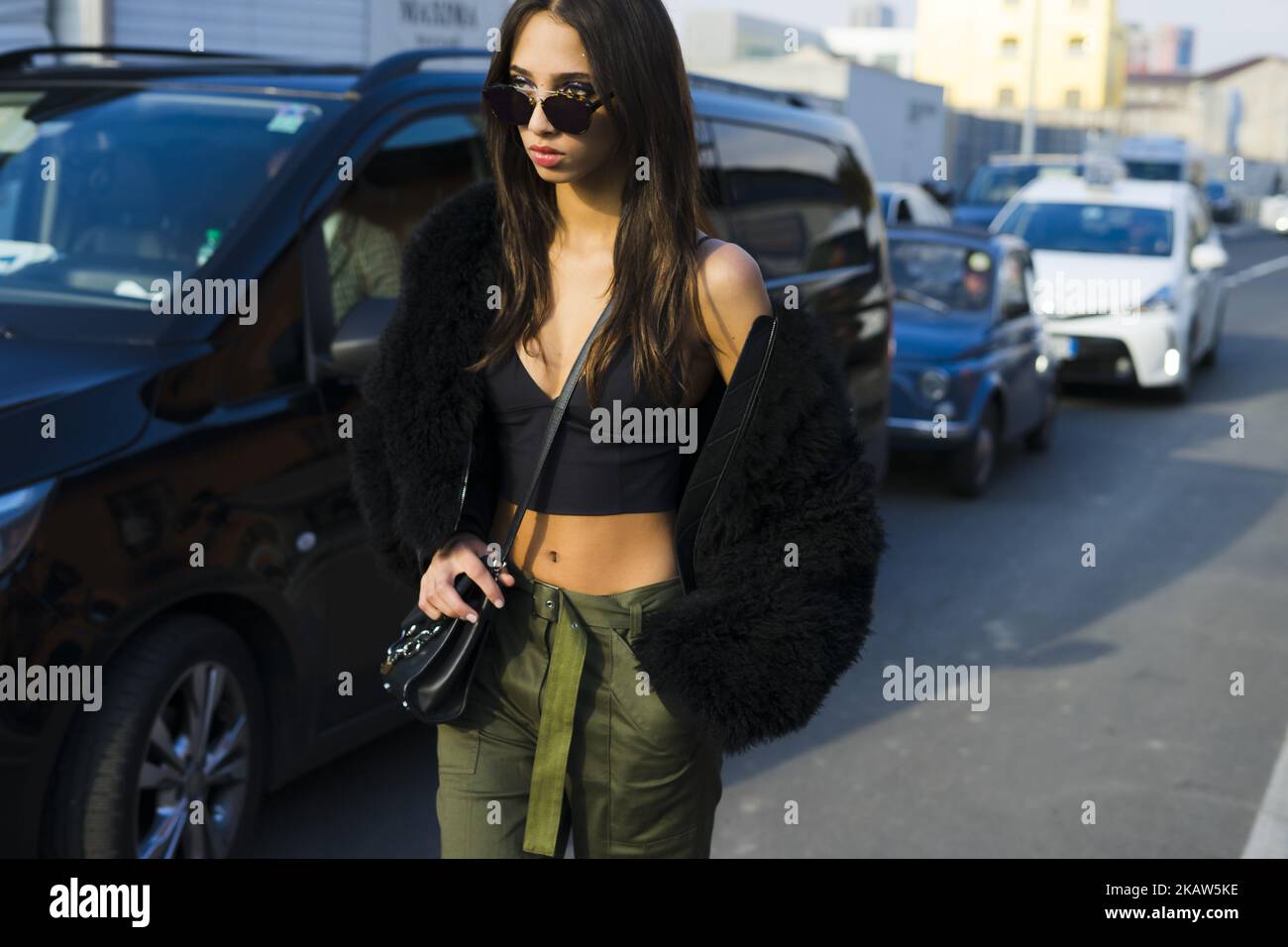La modella Yasmin Wijnaldum indossa occhiali da sole neri, una giacca in pelliccia di Fendi nera sulla spalla, un top in bralette nere, pantaloni verdi e sneaker nere dopo lo spettacolo delle DSquared2:00 durante la settimana della Moda uomo di Milano Autunno/Inverno 2018/19 del 14 gennaio 2018 a Milano. (Foto di Nataliya Petrova/NurPhoto) Foto Stock