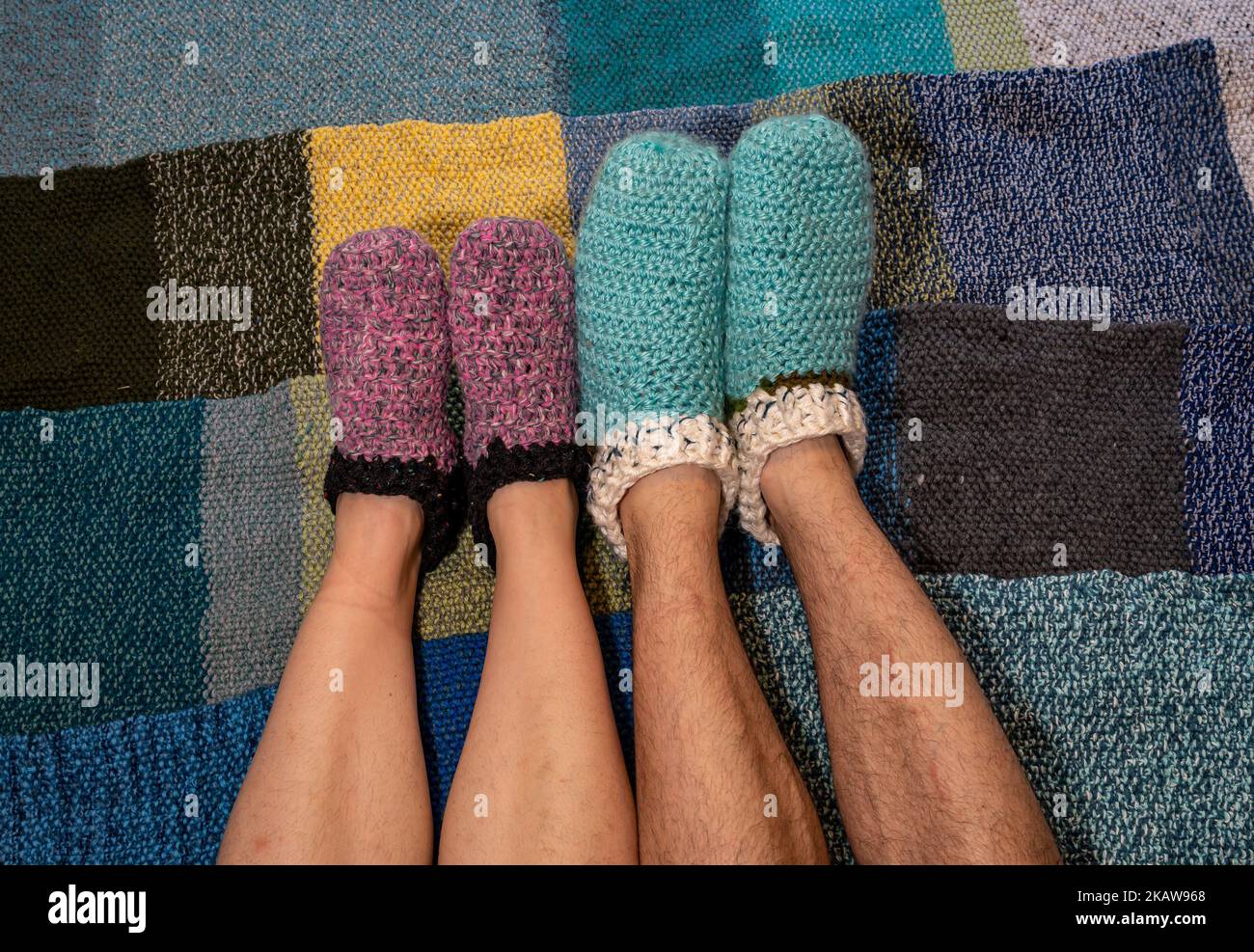 Piedi dell'uomo e di una donna che indossano calde pantofole fatte a mano in lana, che rimangono calde in inverno Foto Stock
