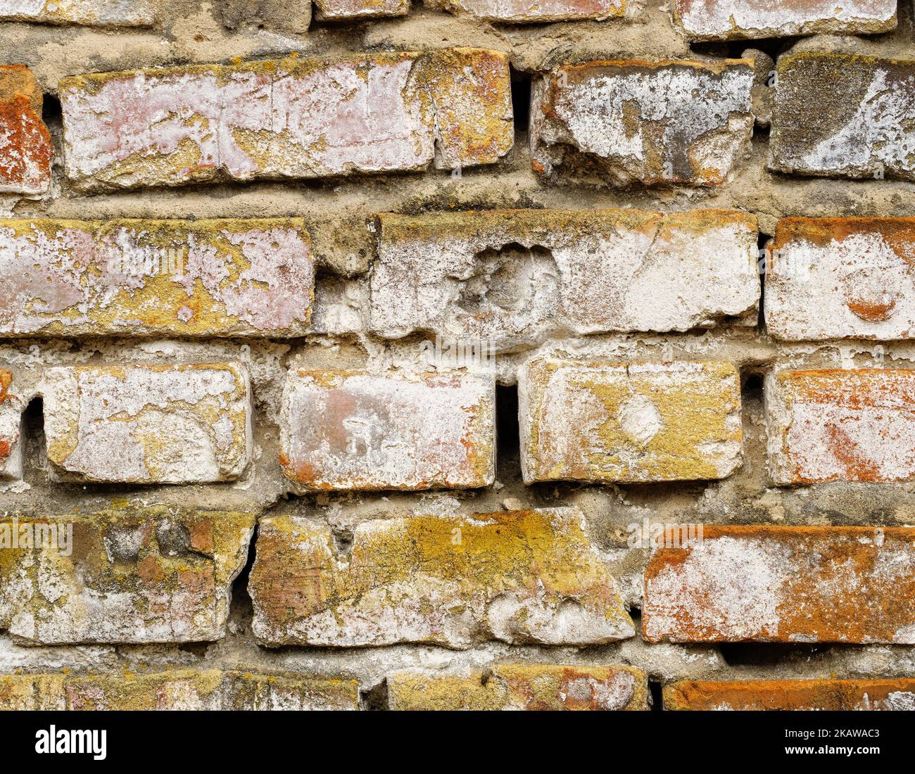 Il vecchio muro di mattoni è crollato e battuto dalle intemperie Foto Stock