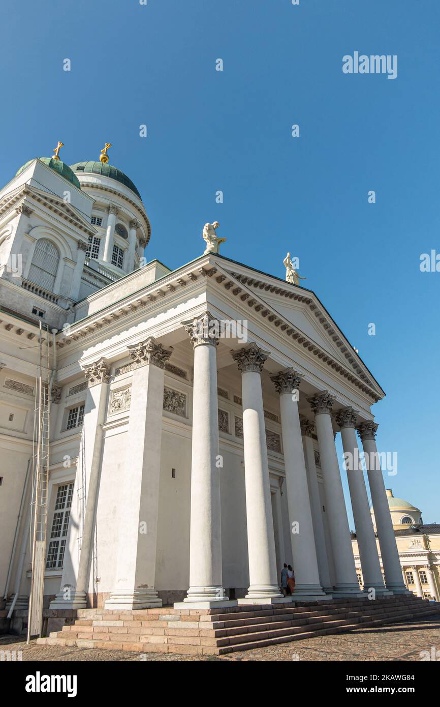 Helsinki, Finlandia - 19 luglio 2022: Lato nord della cattedrale di pietra bianca contro il cielo blu. Frontone di sostegno colonne con 2 statue apostolo. 2 cupola verde Foto Stock