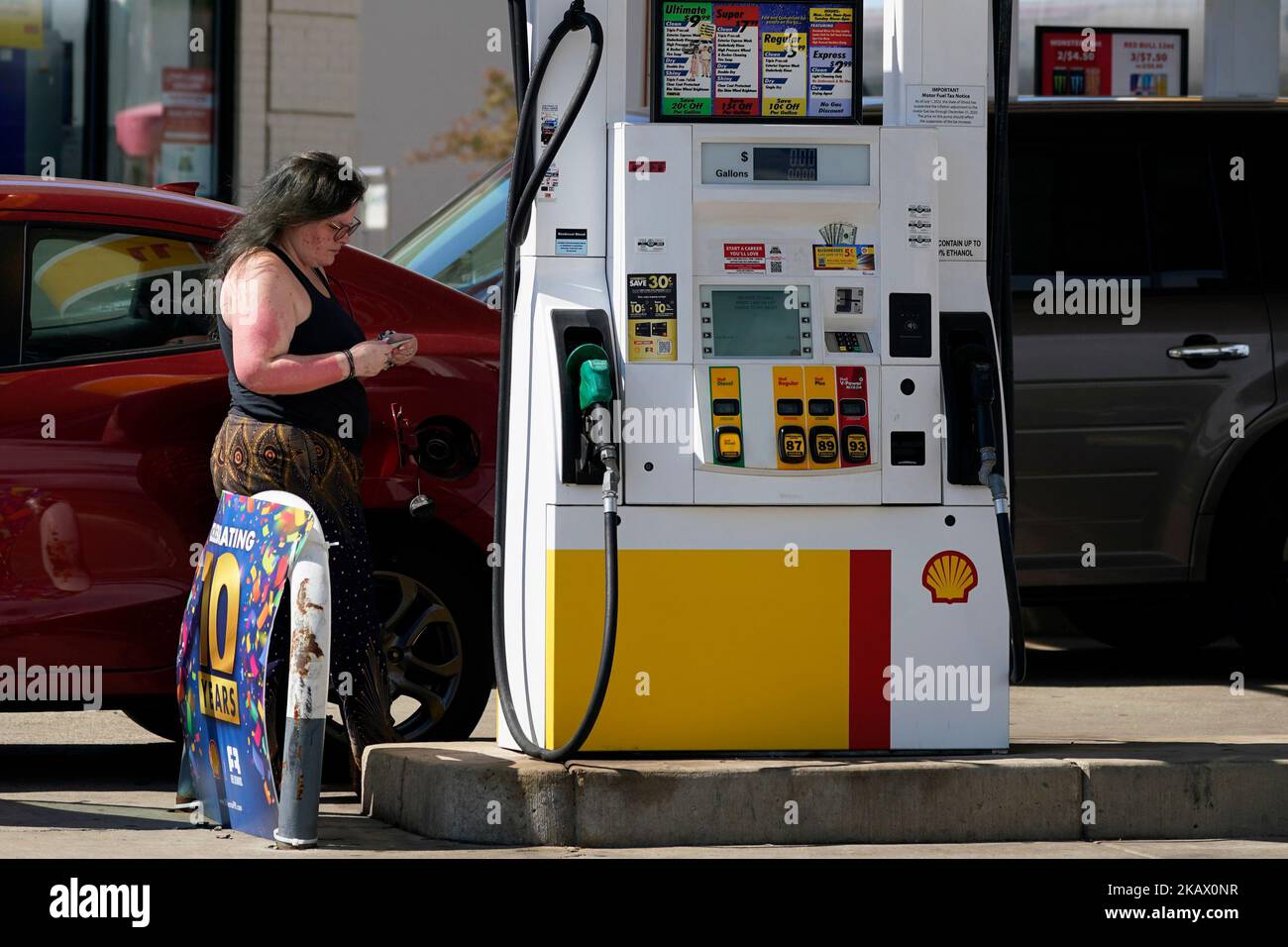 Una vista di una donna che attende dal distributore di carburante in una stazione di servizio Foto Stock