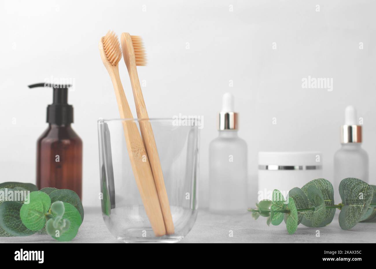 Due spazzolini da denti in legno in un vaso di vetro trasparente. Cura orale Foto Stock