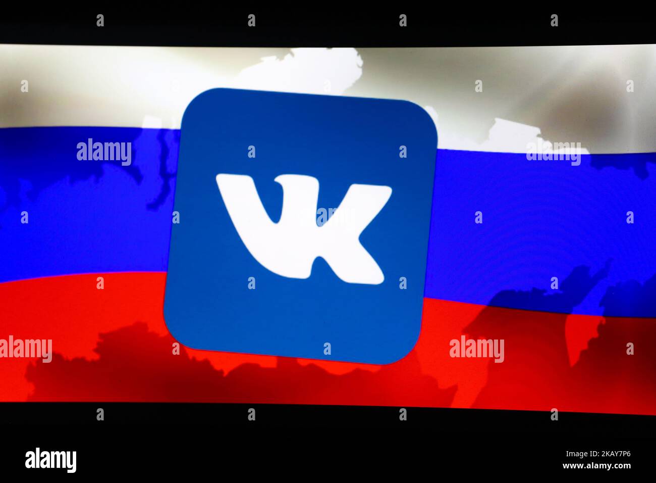 Il logo di VK (VKontakte) con una bandiera russa sullo sfondo è visto su uno schermo. (Foto di Alexander Pohl/NurPhoto) Foto Stock