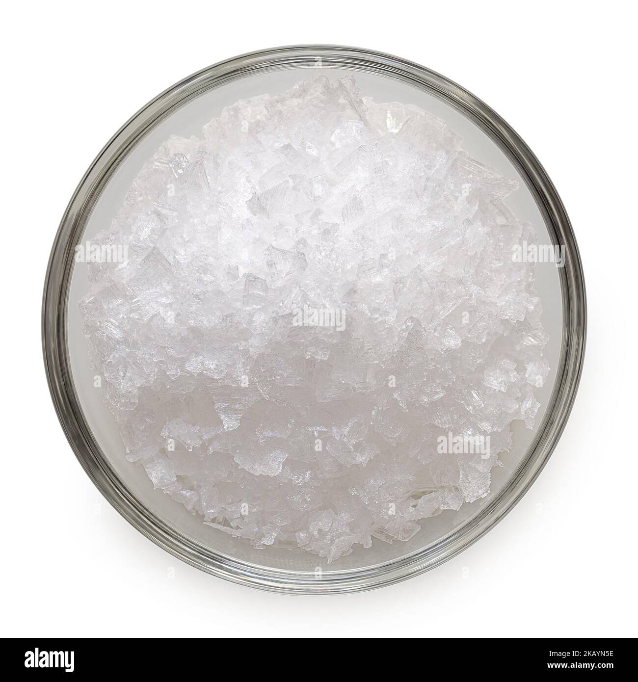 Scaglie di sale marino in una ciotola di vetro isolata su bianco. Vista dall'alto. Foto Stock