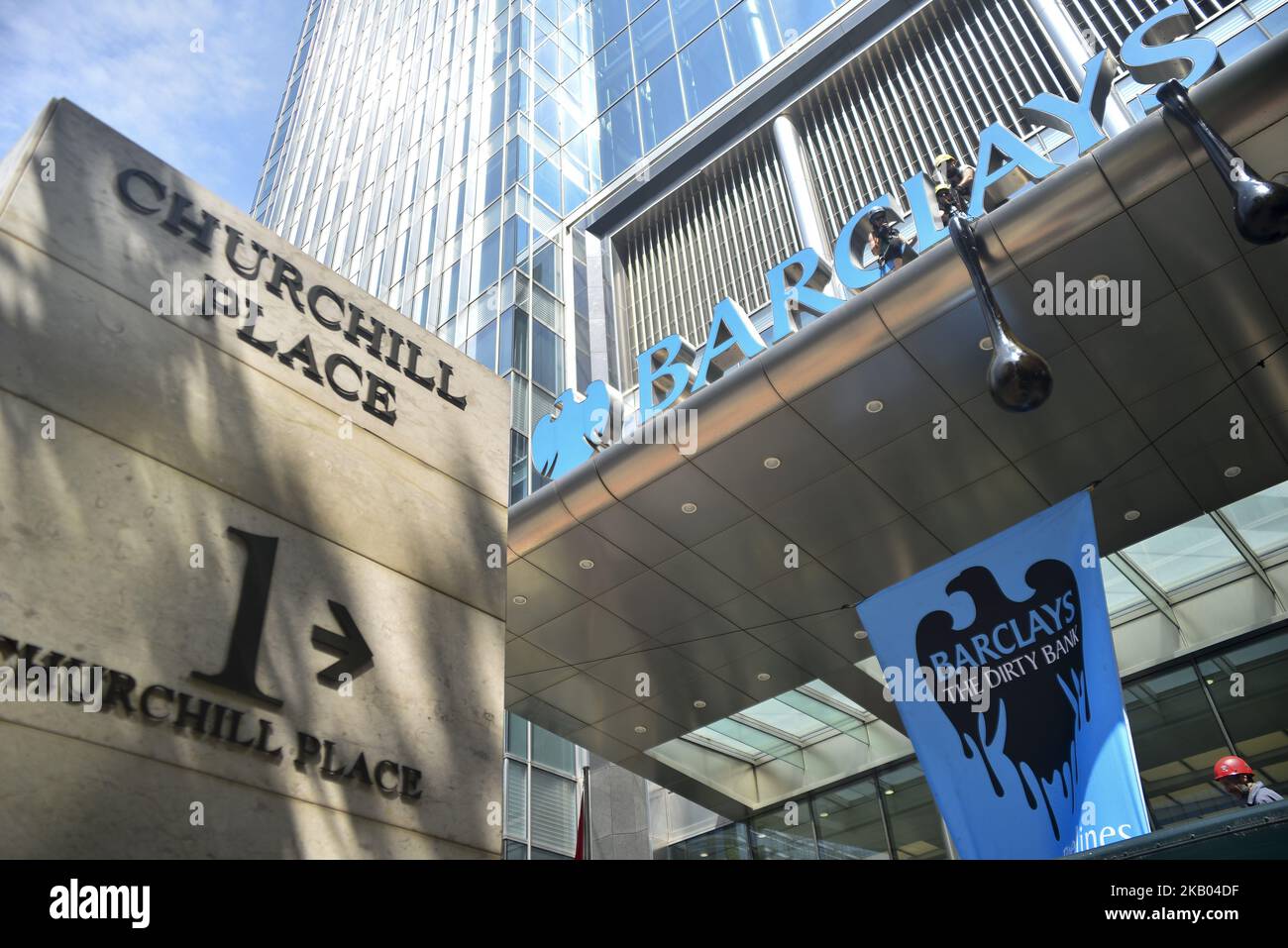 Gli attivisti di Greenpeace si riuniscono all'ingresso principale dei quartieri storici della banca Barclays a Canary Wharf per protestare contro il rifiuto della banca di interrompere il finanziamento di gasdotti che portano il petrolio dalle sabbie bituminose canadesi al mercato negli Stati Uniti e in Asia, Londra il 19 luglio 2018. Gli attivisti hanno scalato l'ingresso per riparare il segnale dei capofateri in un effetto di gocciolamento di petrolio così come altri che entrano nell'edificio vestito da banchieri mentre suonano messaggi registrati dai clienti di Barclays che sono in opposizione al finanziamento della banca dei gasdotti delle sabbie bituminose. (Foto di Alberto Pezzali/NurPhoto) Foto Stock