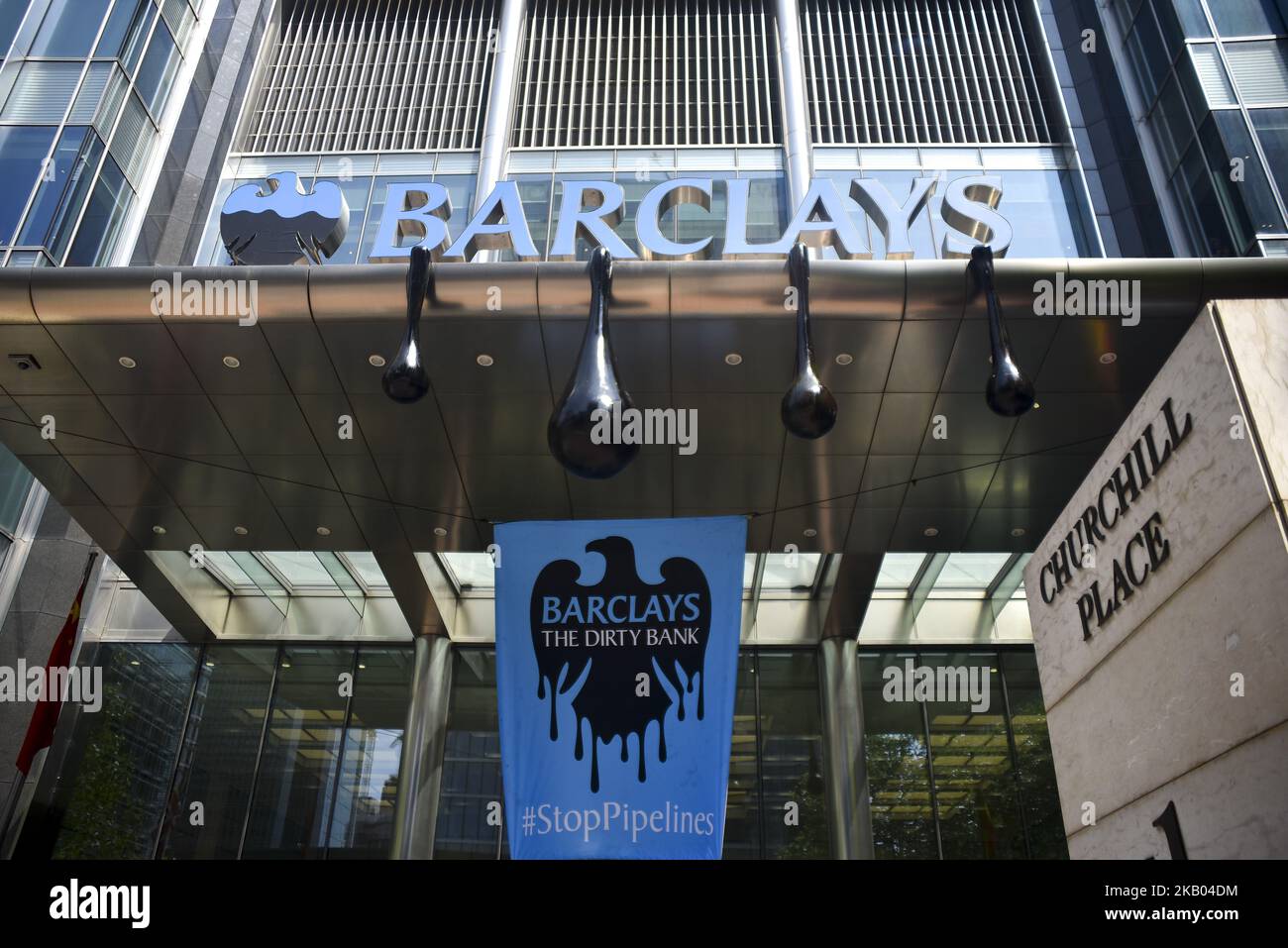 Gli attivisti di Greenpeace si riuniscono all'ingresso principale dei quartieri storici della banca Barclays a Canary Wharf per protestare contro il rifiuto della banca di interrompere il finanziamento di gasdotti che portano il petrolio dalle sabbie bituminose canadesi al mercato negli Stati Uniti e in Asia, Londra il 19 luglio 2018. Gli attivisti hanno scalato l'ingresso per riparare il segnale dei capofateri in un effetto di gocciolamento di petrolio così come altri che entrano nell'edificio vestito da banchieri mentre suonano messaggi registrati dai clienti di Barclays che sono in opposizione al finanziamento della banca dei gasdotti delle sabbie bituminose. (Foto di Alberto Pezzali/NurPhoto) Foto Stock