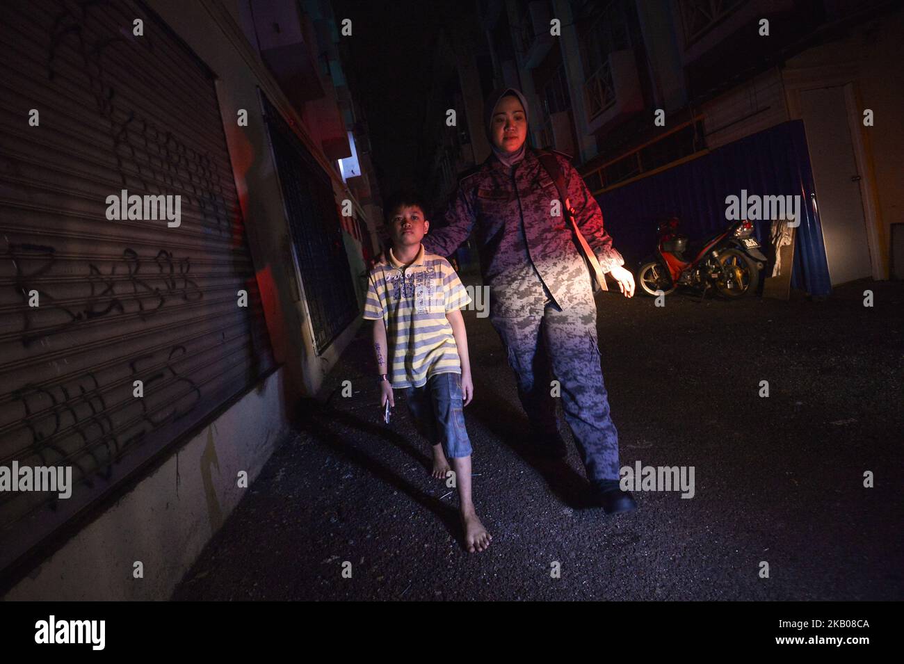 Un ufficiale dell'immigrazione (R) accompagna un ragazzo (L) che sua madre ha arrestato durante un raid a Subang Jaya, al di fuori di Kuala Lumpur, Malesia, 29 luglio 2018. Circa 157 migranti non documentati sono stati arrestati per vari reati dal Dipartimento dell'immigrazione durante un raid nell'ambito dell'operazione "Ops Mega 3,0" contro lavoratori migranti non documentati. (Foto di Zahim Mohd/NurPhoto) Foto Stock