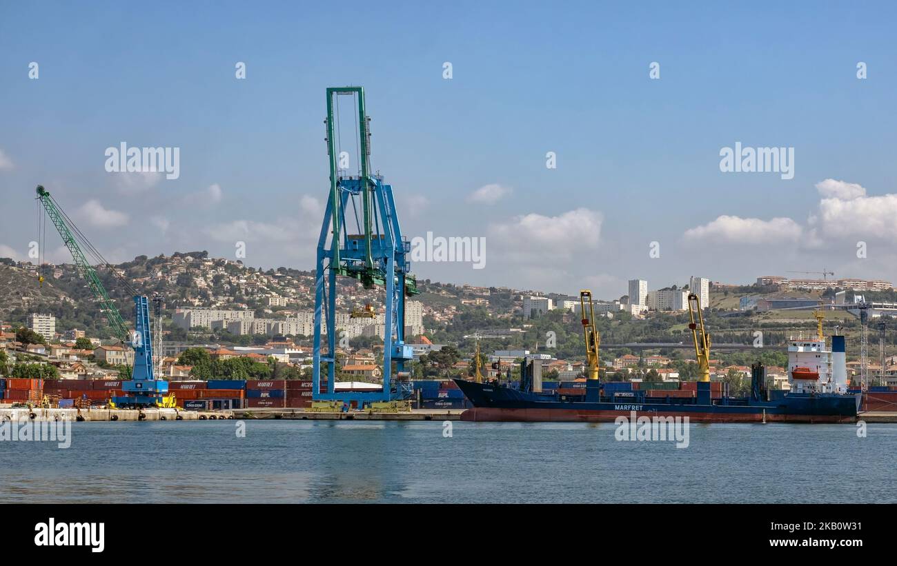 MARSIGLIA, FRANCIA - 18 MAGGIO 2018: Nave da carico container e gru nel molo commerciale con la città sullo sfondo Foto Stock