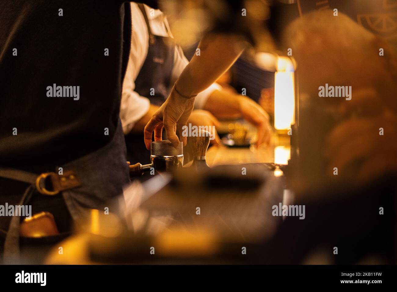 Primo piano del barista che manometta il caffè appena macinato in un filtro porta Foto Stock