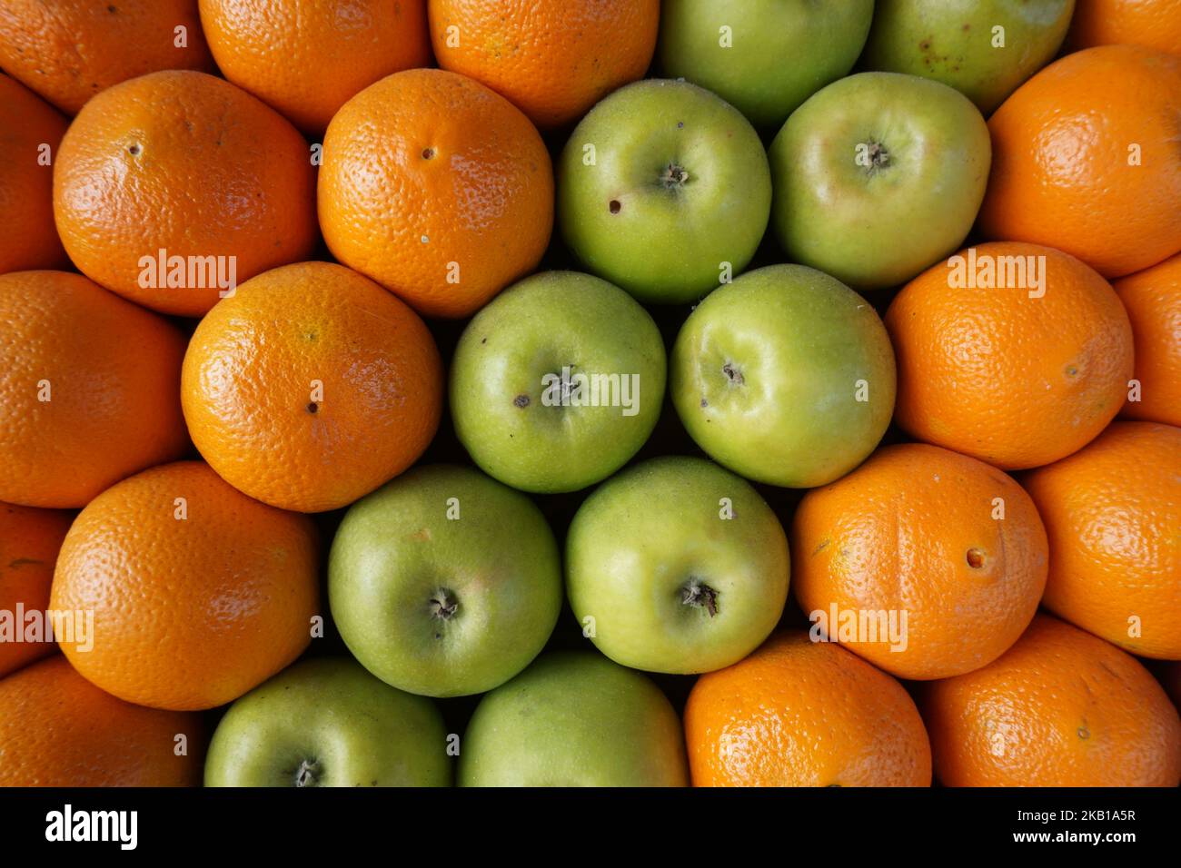 mele verdi e arance disposte diagonalmente Foto Stock