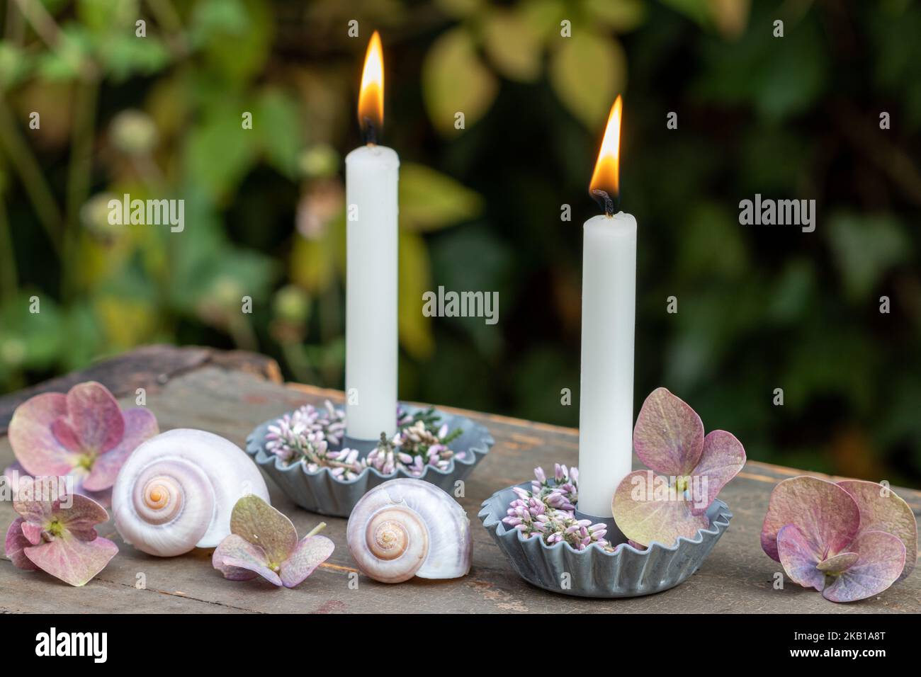 sistemazione romantica con candele bianche, corona di erica e fiori di ortensia Foto Stock