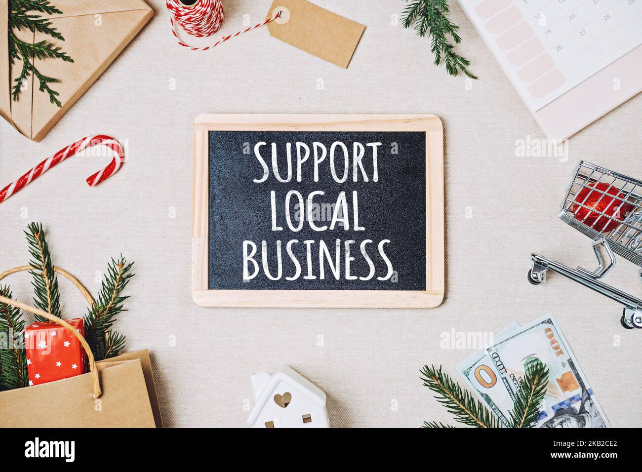 Supporto del testo dell'azienda locale scritto sulla lavagna. Piatto Lay con supporto Preventivo commerciale locale, decorazione natalizia e shopping bag, scatole regalo e. Foto Stock