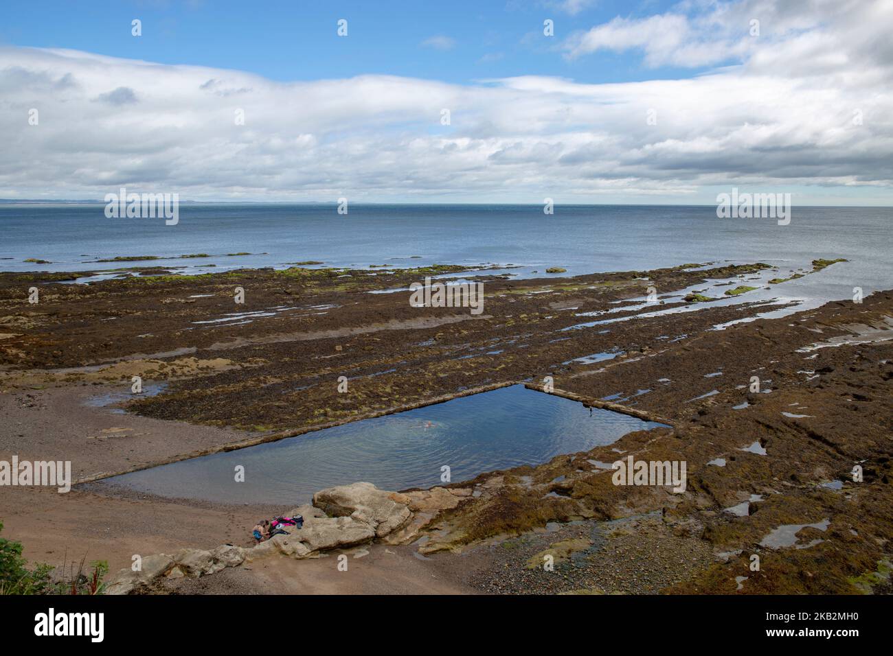 Bagnanti nella piscina naturale di acqua salata sulla costa di St Andrews in Scozia in estate Foto Stock