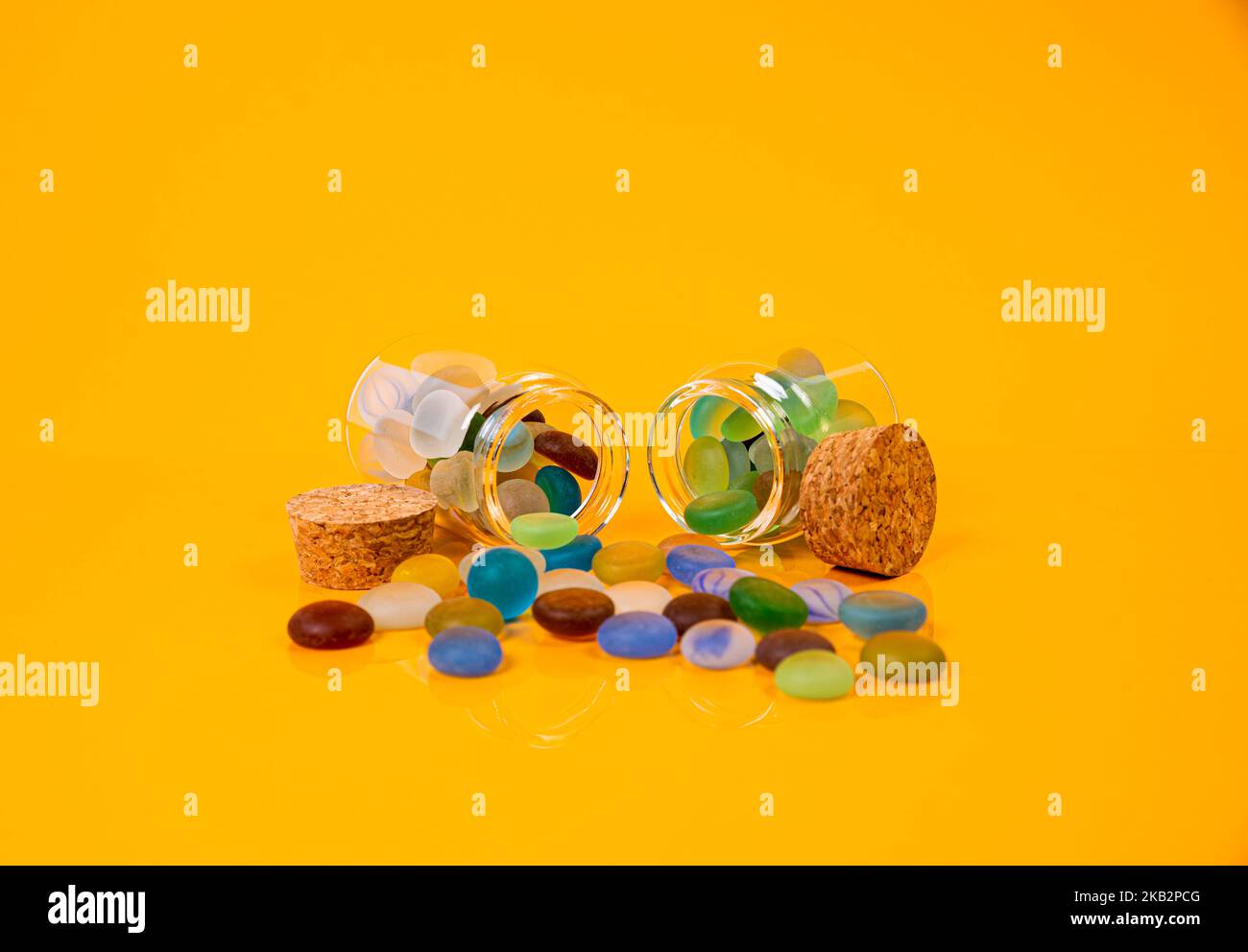 pietre colorate in vetro in vaso in secchio su sfondo arancione isolato Foto Stock