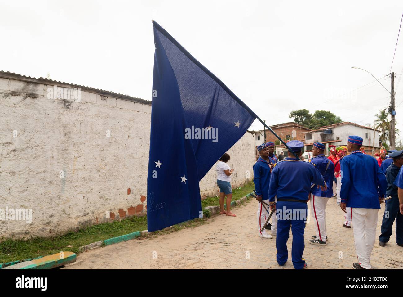 Saubara, Bahia, Brasile - 06 agosto 2022: I membri del gruppo culturale Encontro de Chegancas indossano abiti bianchi e blu e portano una bandiera. Saubara, B. Foto Stock