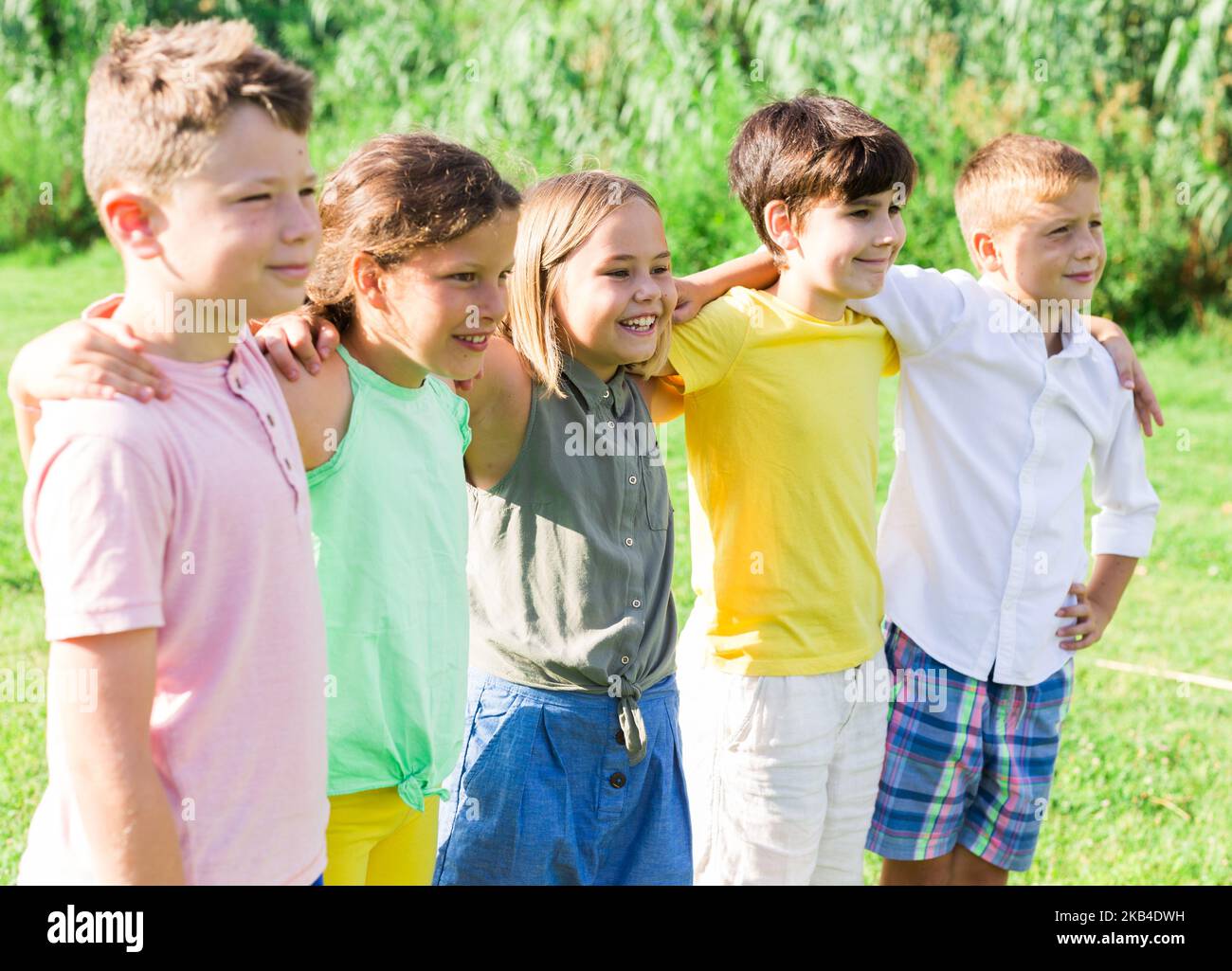 Cinque bambini seduti sull'erba Foto Stock