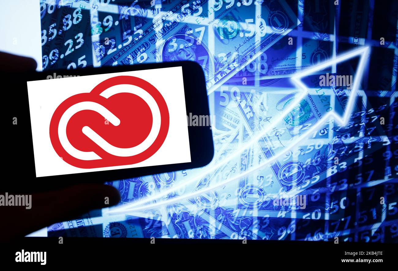 Il logo di Adobe Cloud viene visualizzato sullo schermo di uno smartphone accanto a uno schermo con un'illustrazione del mercato azionario. Adobe è elencato in Nasdaq. Il Nasdaq è la seconda borsa più grande del mondo dopo la borsa di New York. (Foto di Alexander Pohl/NurPhoto) Foto Stock