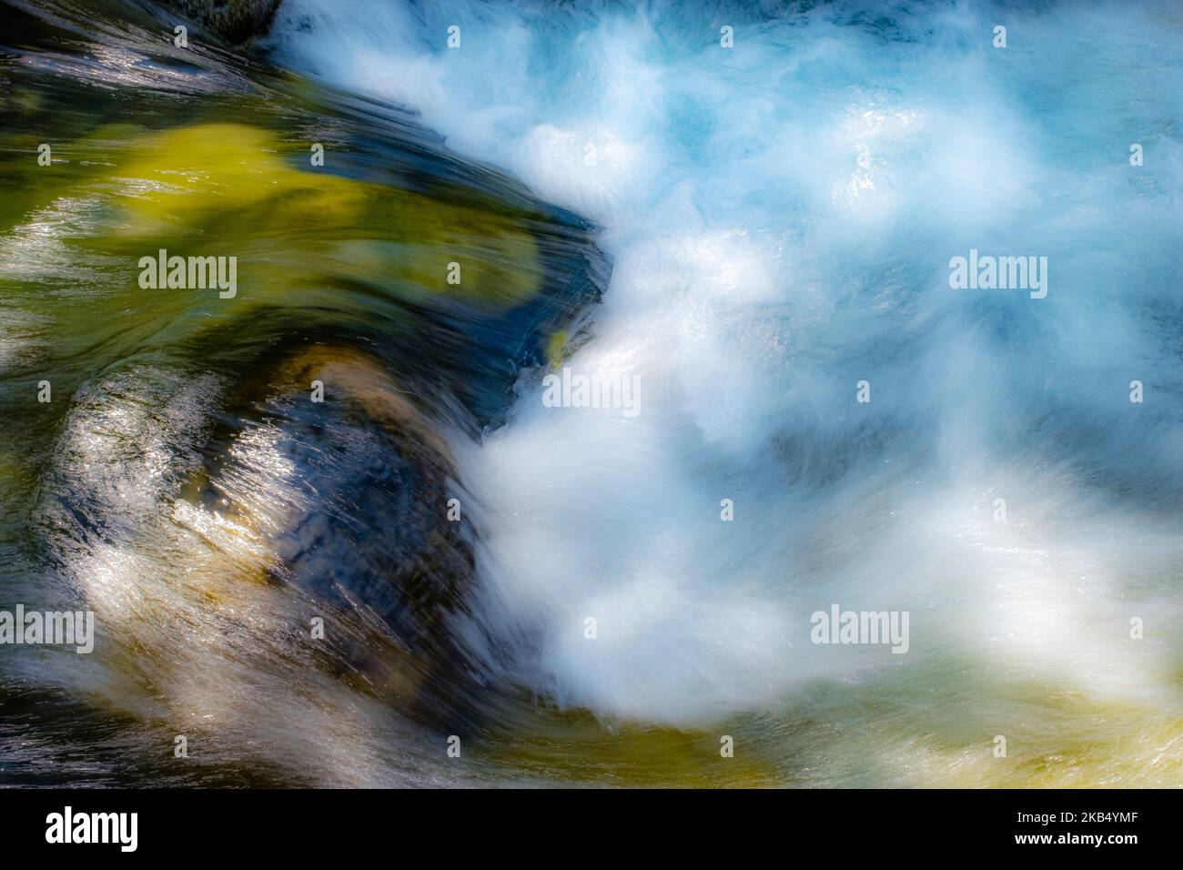 lunga esposizione immagine astratta di acqua vorticosa in un fiume di montagna di acqua cristallina, toni verdi, blu e bianchi Foto Stock