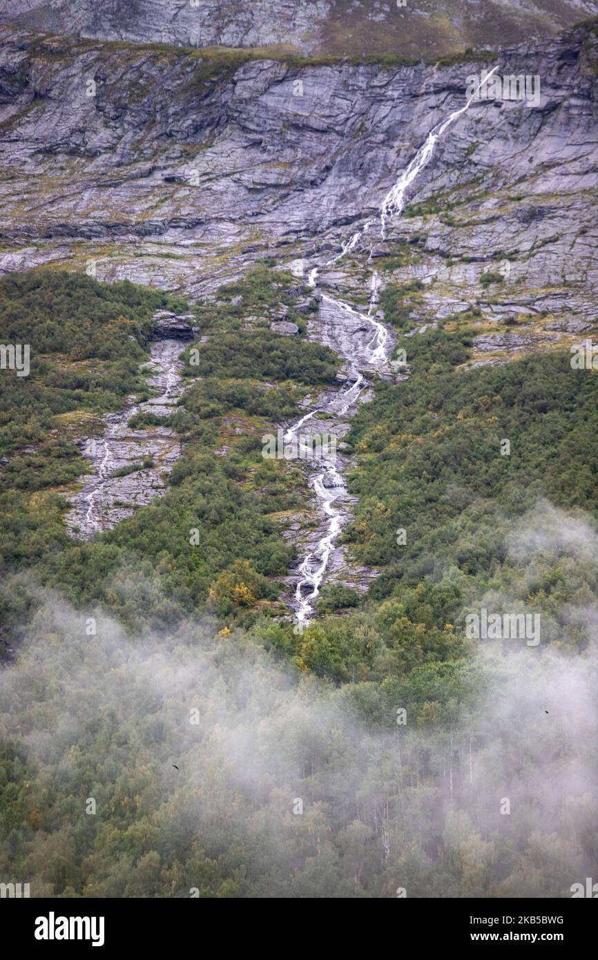 Belle cascate all'interno di natura intensa in uno scenario drammatico con nuvole o verde ambiente naturale forestale, visto ai fiordi in Norvegia con foreste e ripide montagne. Le acque provenienti dalle cime montuose e dai ghiacciai d'alta quota finiscono attraverso il fiume Valldola fino ai fiordi e al mare nella zona di Valldal e Valldalen il 31 agosto 2019. (Foto di Nicolas Economou/NurPhoto) Foto Stock