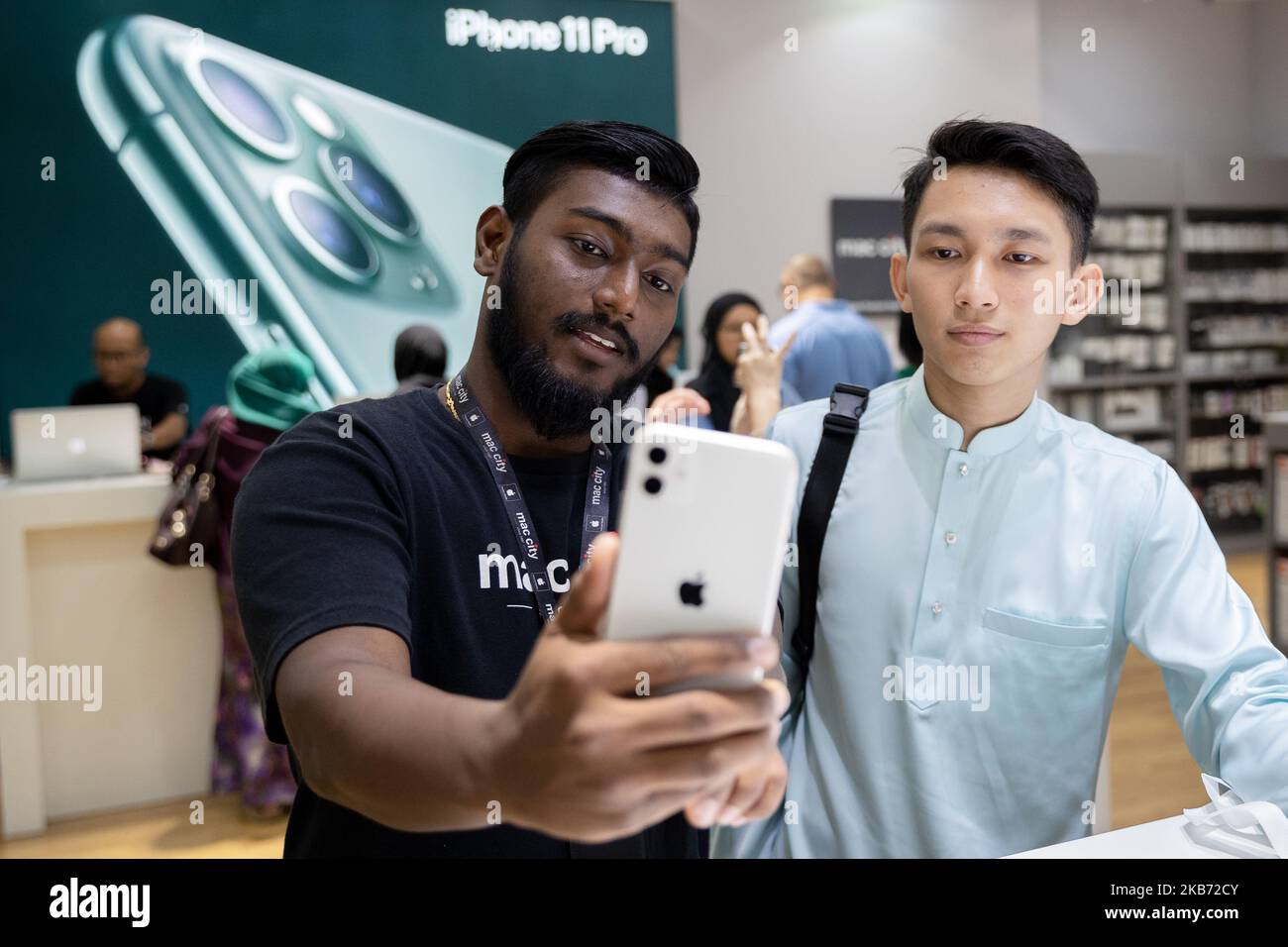 Un dipendente, a sinistra, mostra a un cliente le caratteristiche di un iPhone 11 presso l'Apple Store durante un evento di lancio del prodotto a Kuala Lumpur, Malesia, venerdì 27 settembre 2019. I nuovi iPhone di Apple con miglioramenti della fotocamera e una maggiore durata della batteria sono in vendita oggi stesso. (Foto di Chris Jung/NurPhoto) Foto Stock