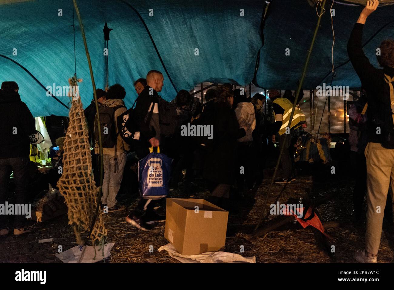 Gli attivisti ambientali si riparano dalla pioggia durante la notte con grandi teloni e striscioni in plastica, uno dei quali recita 'Siamo tutti nella stessa barca' lunedì 7 ottobre 2019, Quando diverse centinaia di attivisti ecologisti membri del movimento internazionale Extinction Rebellion (XR) ha lanciato l'occupazione di Place du Chatelet e il Pont au Change a Parigi, al fine di allertare la popolazione e le autorità francesi e internazionali sull'emergenza climatica di fronte ai governi inoperanti affrontare il riscaldamento globale. Tale azione rientra nel quadro dell'azione internazionale Foto Stock