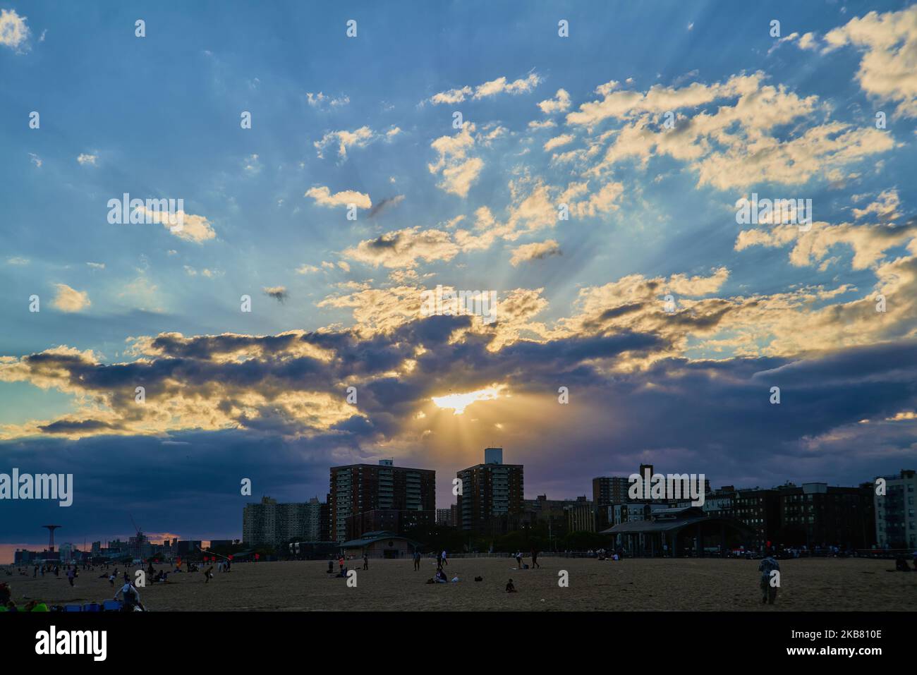 Raggi di luce sull'isola di coney che sbirciano tra le nuvole in serata Foto Stock