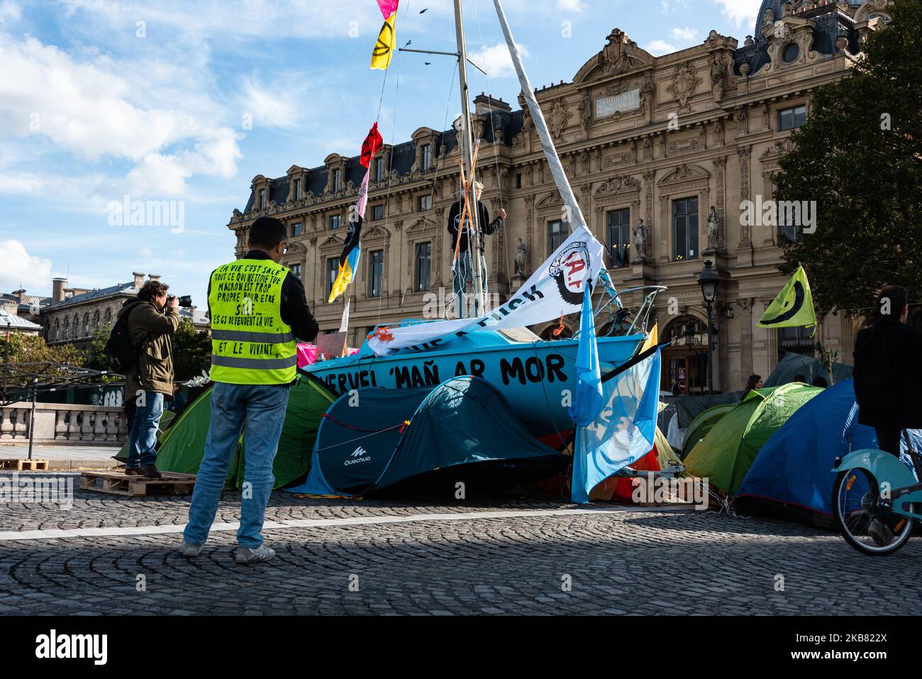 Un protesista del movimento del gilet giallo osserva la nave della ribellione di estinzione seduta nel mezzo del campo del ponte di cambiamento il giovedì 10 ottobre 2019, Come centinaia di attivisti del movimento internazionale di ribellione estinzione stanno attualmente partecipando a un movimento globale per aumentare la consapevolezza del cambiamento climatico occupando a Parigi il luogo di Chatelet e il ponte al cambiamento uno ha iniziato il loro quarto giorno di occupazione di questi luoghi. Per l'occasione e di fronte all'inattività dei governi hanno ampliato l'area del campo di fortuna occupando anche la strada di riv Foto Stock