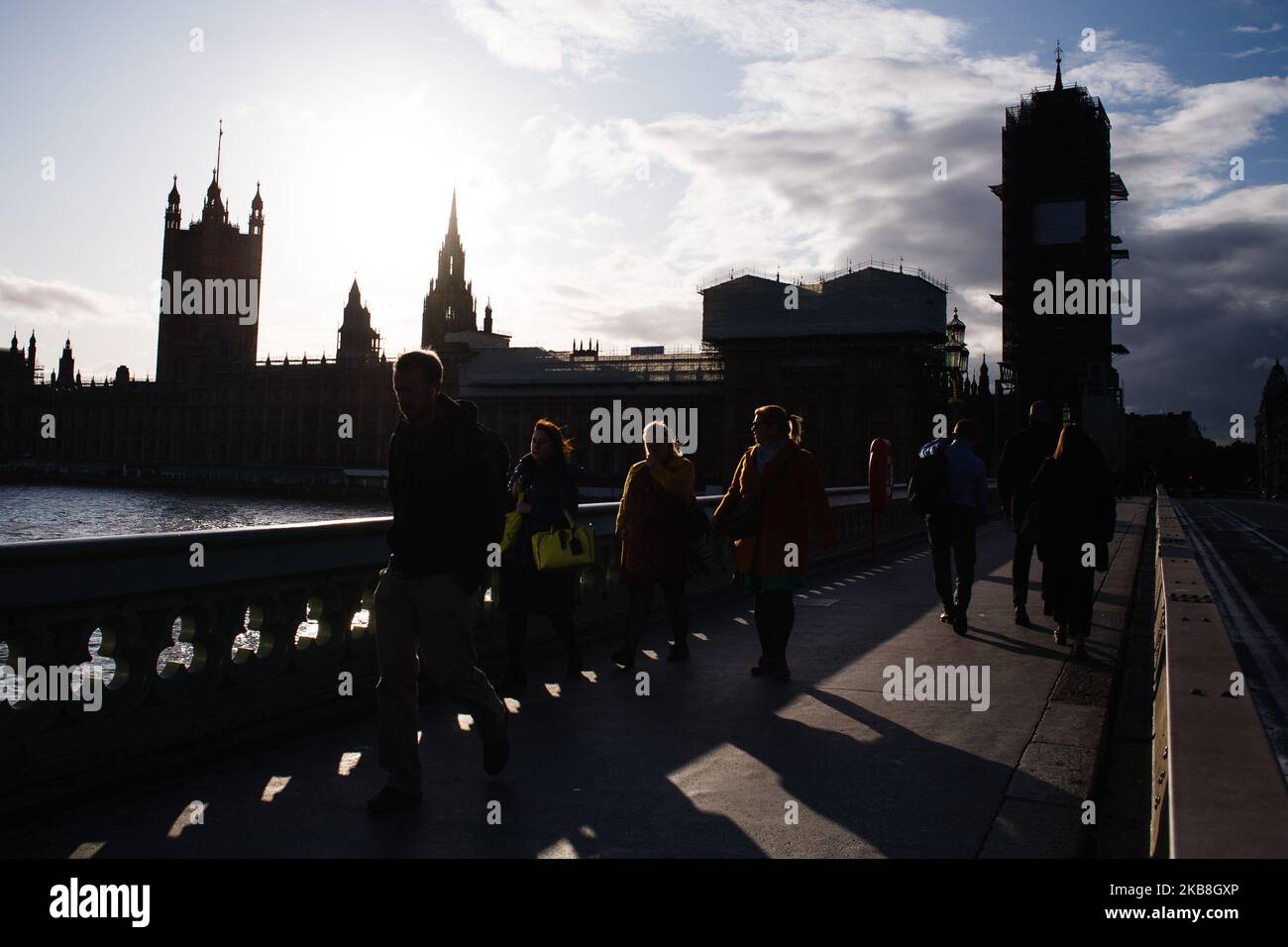 La gente attraversa il Westminster Bridge di fronte al Parlamento mentre il sole inizia a tramontare a Londra, in Inghilterra, il 17 ottobre 2019. Il primo ministro Boris Johnson ha concordato oggi un nuovo accordo di ritiro con l'Unione europea, ma non è chiaro se l'accordo passerà un voto sui beni comuni fissato per questo sabato, in una sessione speciale del fine settimana dei parlamentari. Il Partito democratico Unionista (DUP), visto come un influente sostenitore di una sciata di deputati del Partito conservatore pro-Brexit, ha detto senza senso di non sostenere l’accordo. (Foto di David Cliff/NurPhoto) Foto Stock