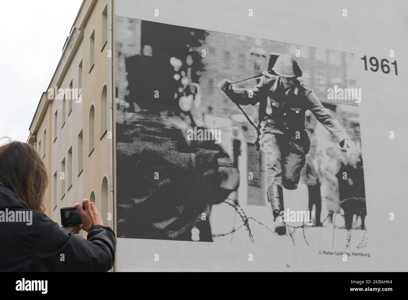 Una donna scatta una foto di un'immagine iconica di Hans Konrad Schumann, una guardia di frontiera della Germania orientale che si è rivolta verso la Germania occidentale durante la costruzione del Muro di Berlino nel 1961, ammira l'edificio vicino al punto in cui un tempo si trovava il Muro di Berlino a Bernauer Strasse, Alla vigilia del prossimo 30th° anniversario della caduta del muro di Berlino. Sabato 9 novembre 2019 a Berlino, Germania. (Foto di Artur Widak/NurPhoto) Foto Stock